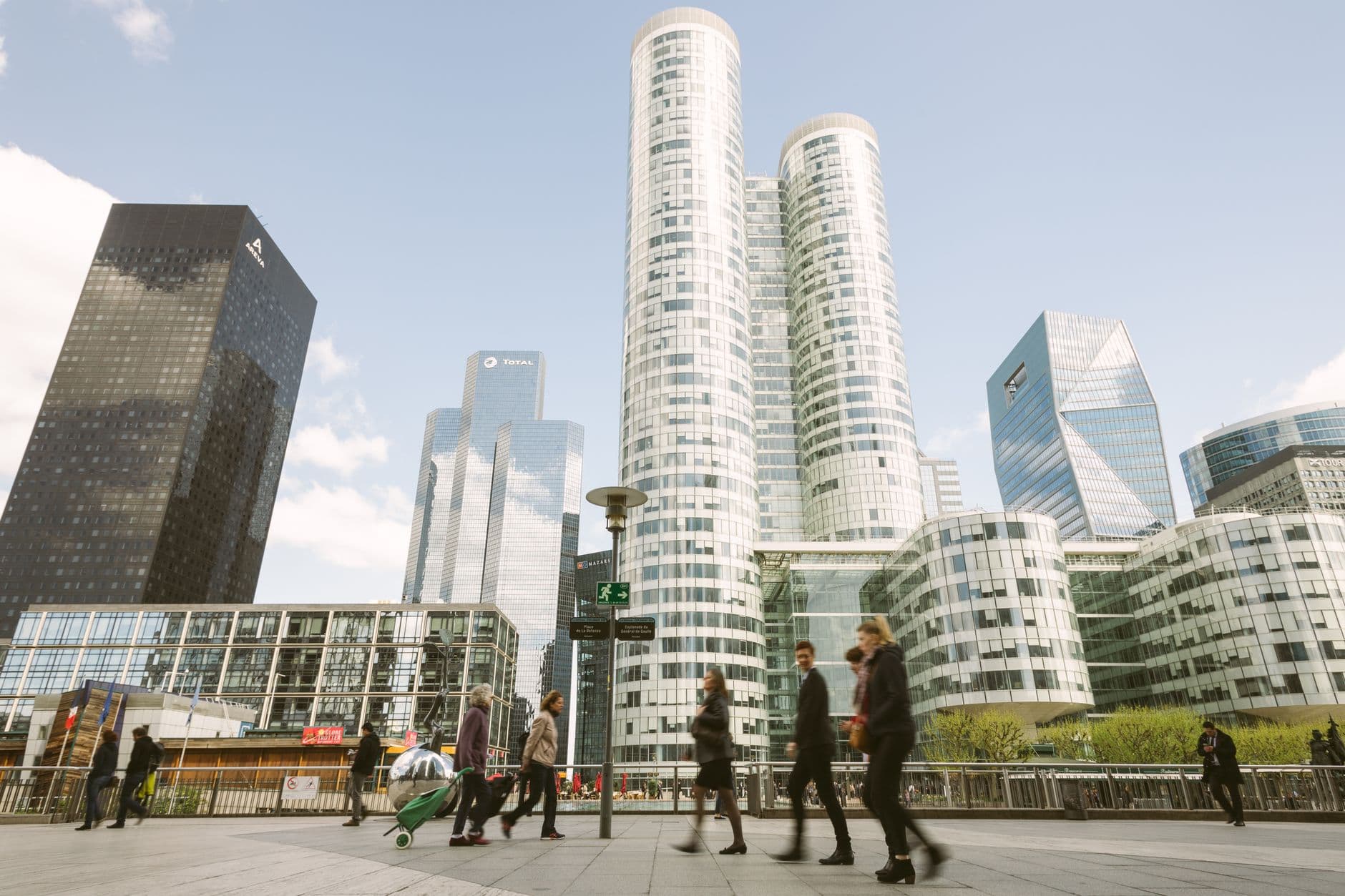 Dynamic cityscape of La Défense towers with people walking in Paris, France.