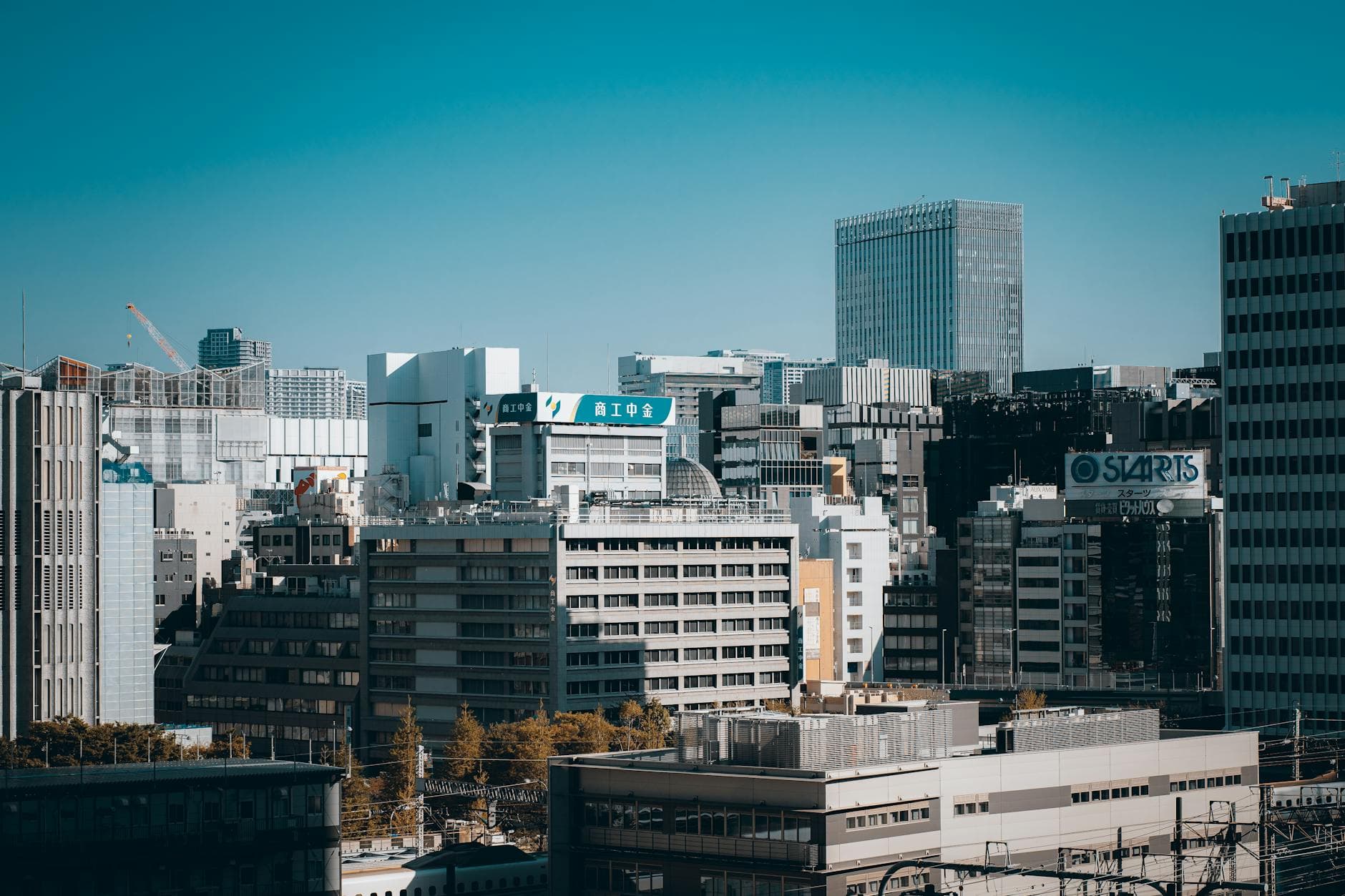 Aerial view of Tokyo's modern skyline features towering buildings and urban architecture under a clear blue sky.