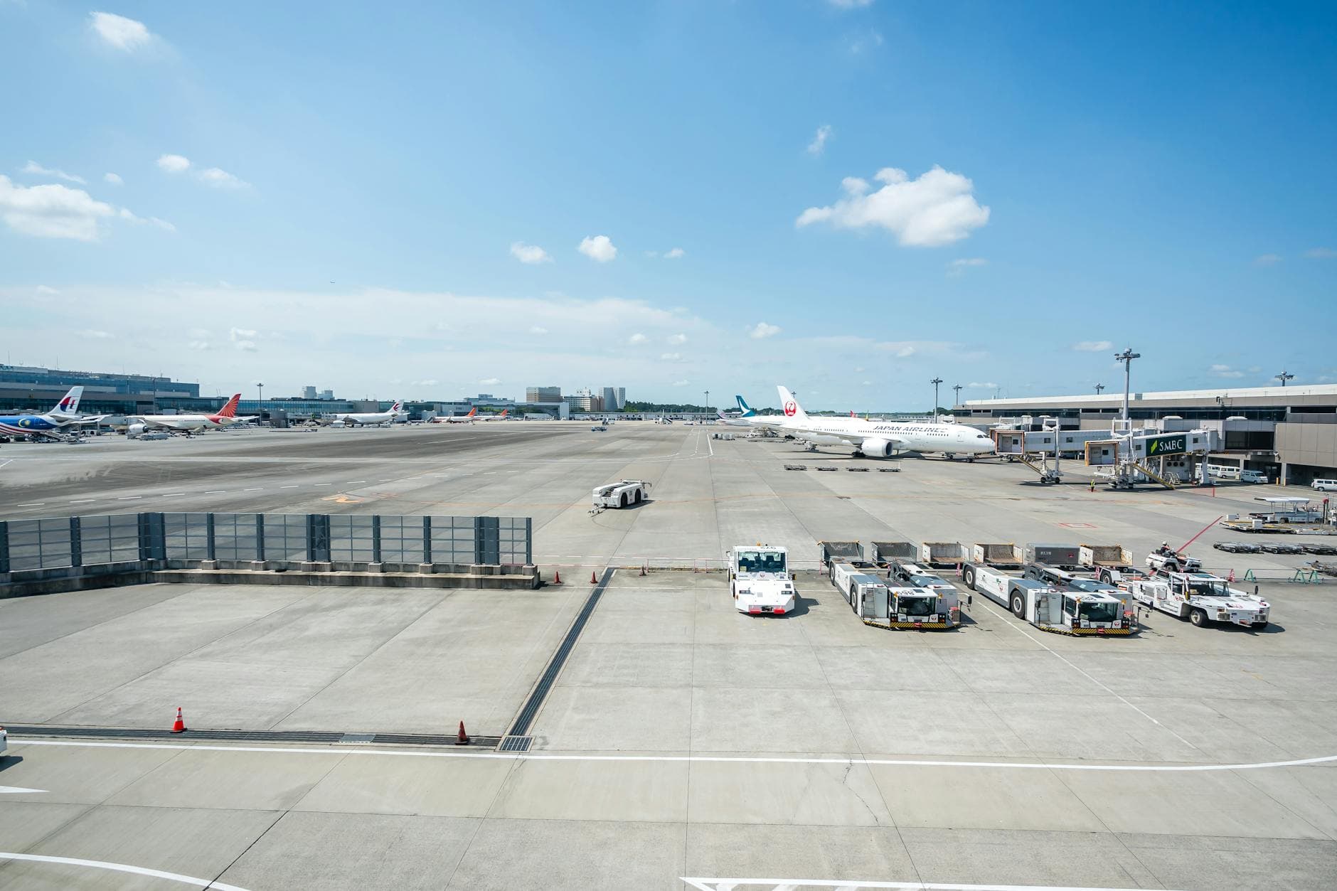 Wide view of a bustling airport apron in Japan under a clear blue sky.