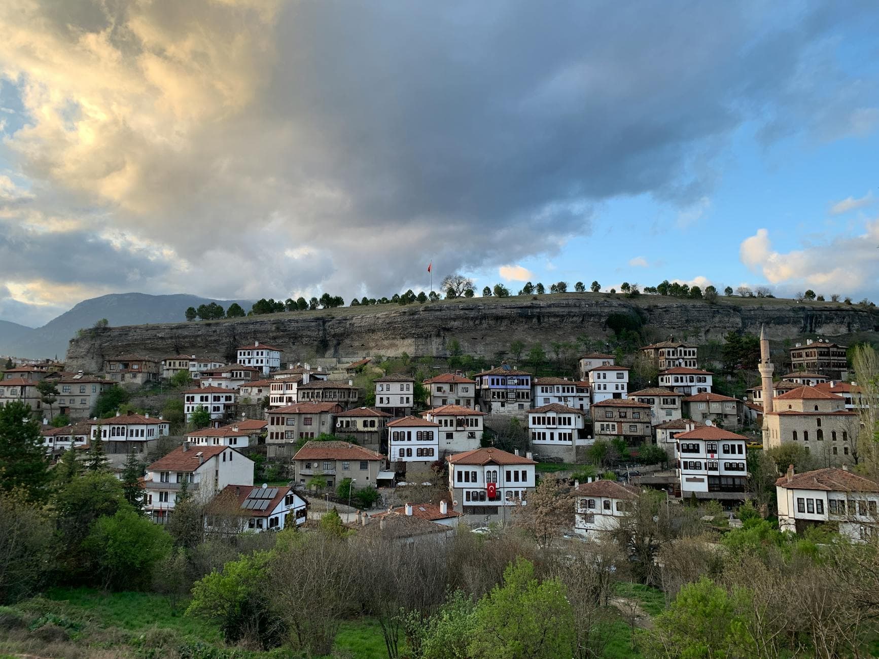 Charming view of historic Ottoman houses in Safranbolu with dramatic sky and lush greenery.