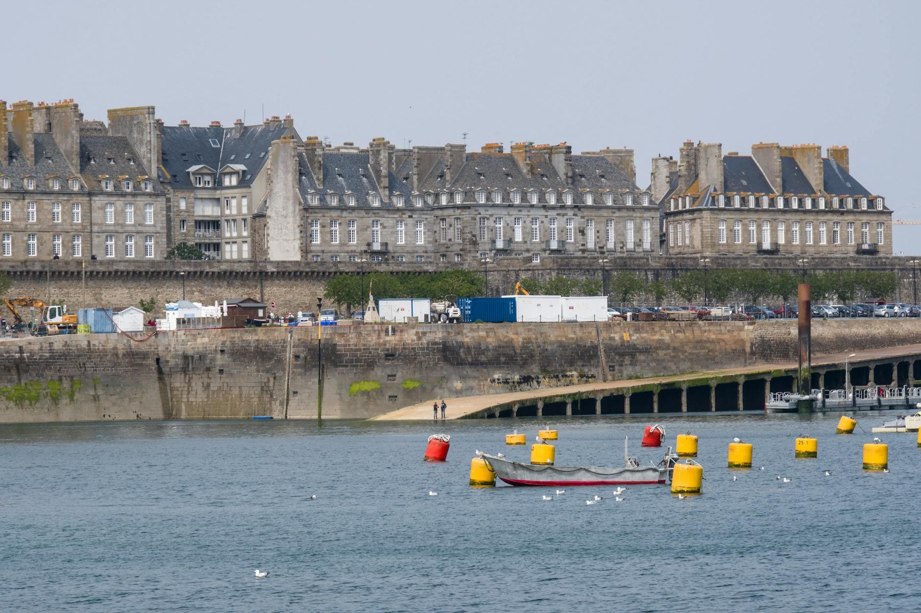 Scenic view of Saint-Malo's historic architecture along the harbor, with colorful buoys and boats in the foreground.