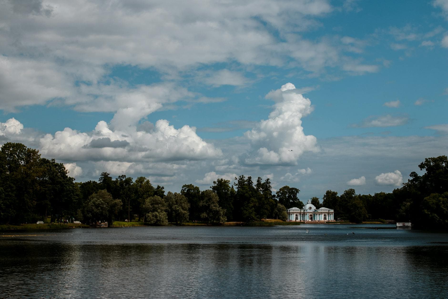 Scenic view of Grotto Pavilion on a lake beneath a vivid blue sky in Catherine Park, St. Petersburg.