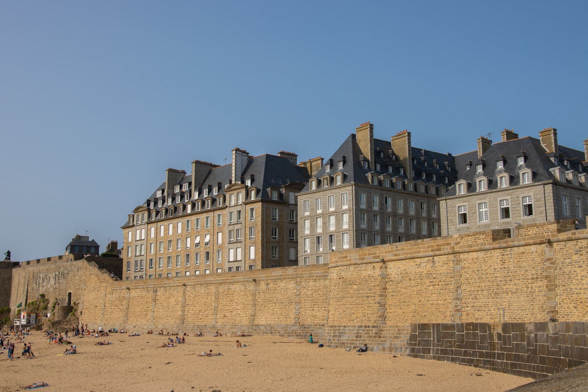 View of historical buildings and stone walls at Saint-Malo beach, Brittany, France.