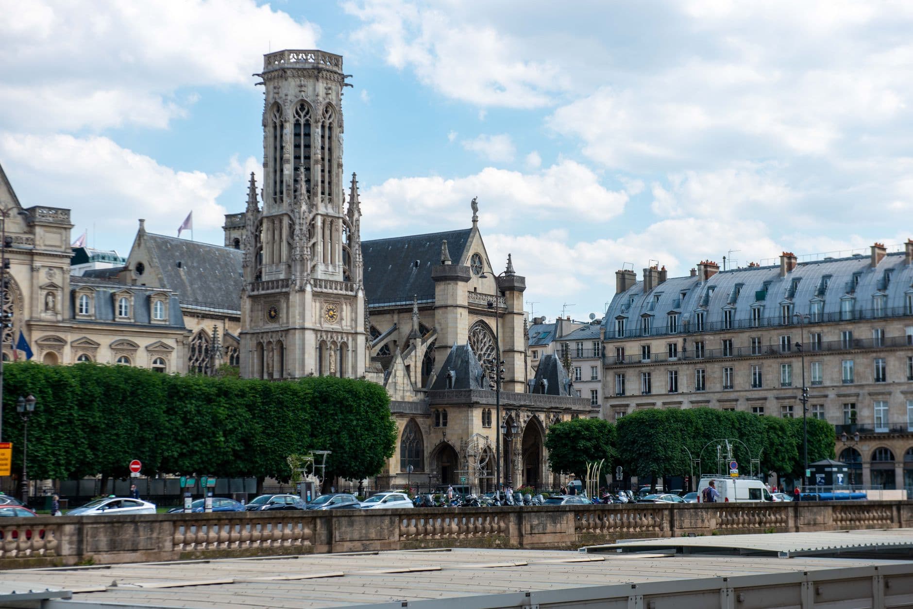 Gothic church and historic buildings under a blue sky in Paris cityscape.