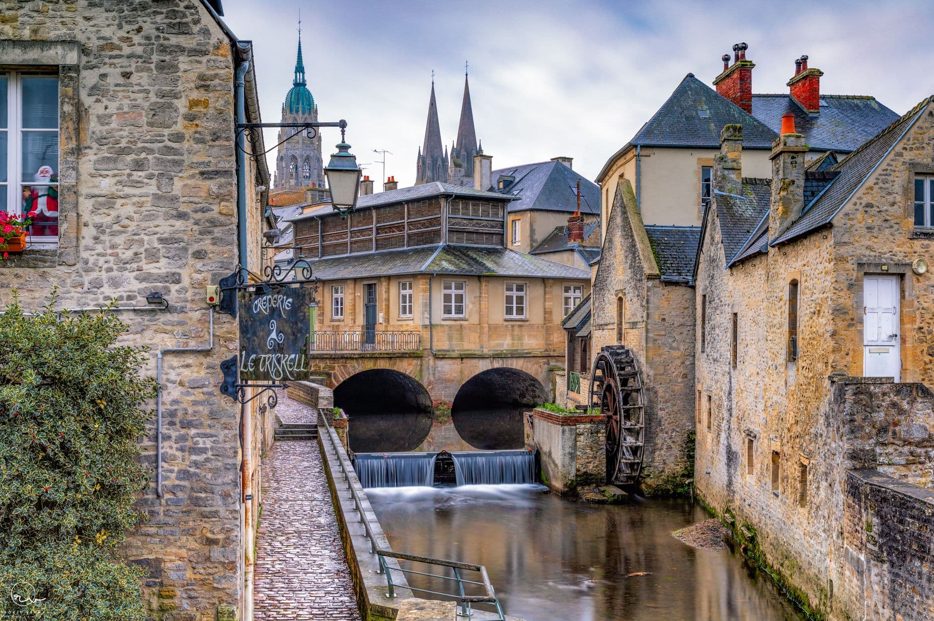 Historic watermill on a picturesque canal in Bayeux, France, showcasing Normandy's charm.