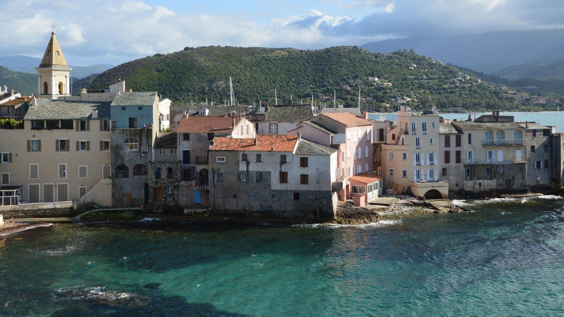 Picturesque coastal view of Saint-Florent, Corsica with historical architecture and clear blue sea.