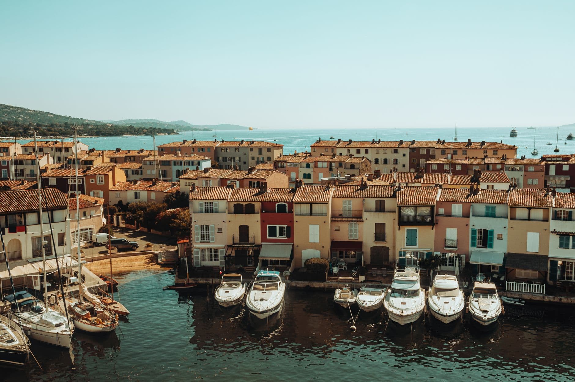 Charming view of colorful waterfront buildings and docked boats on a sunny day in Saint-Tropez, France.