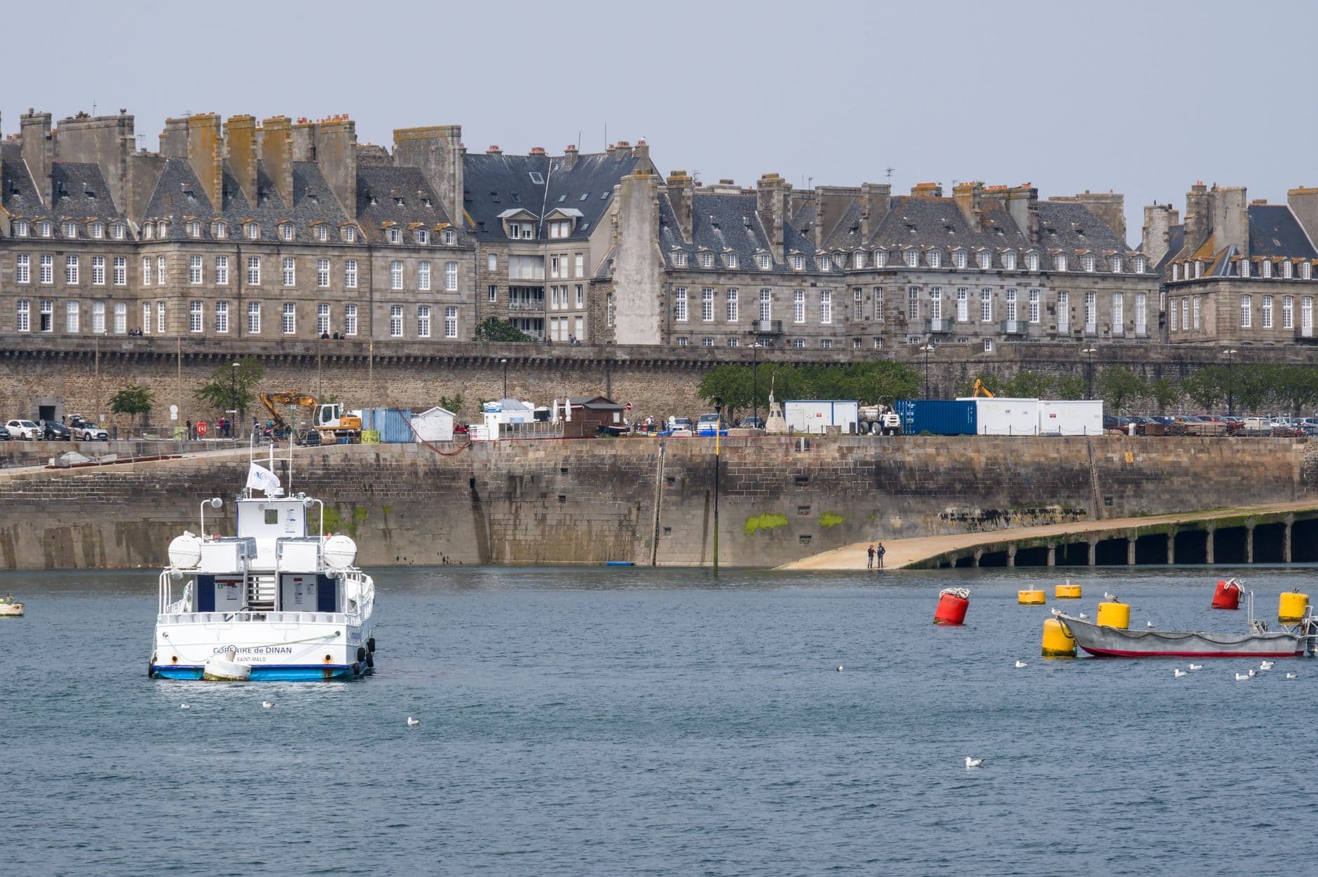 Captivating view of the historic Saint-Malo waterfront, featuring boats and stone buildings.