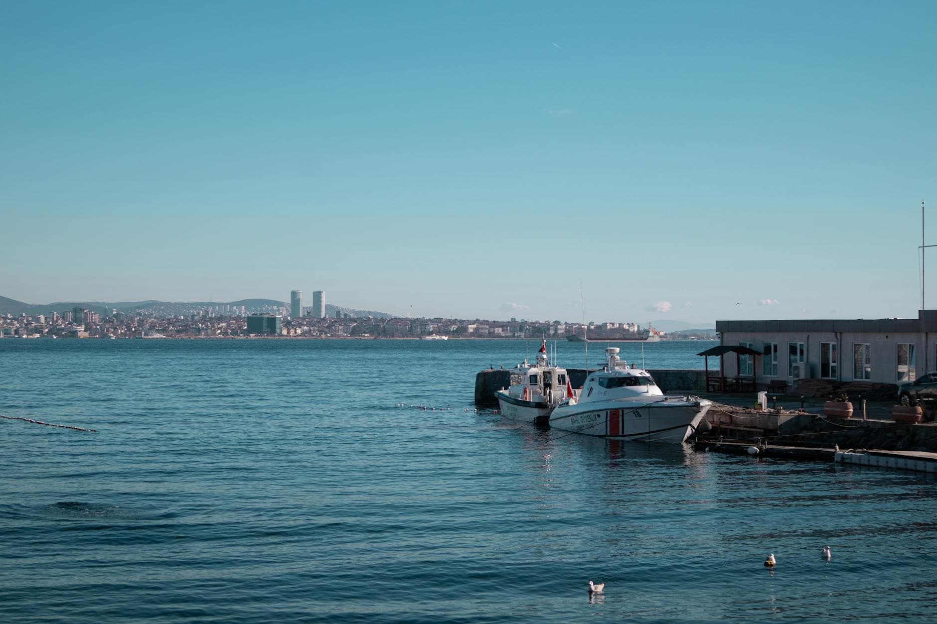 Tranquil photo of the Istanbul coastline with boats and cityscape, showcasing the beauty of the Bosphorus.
