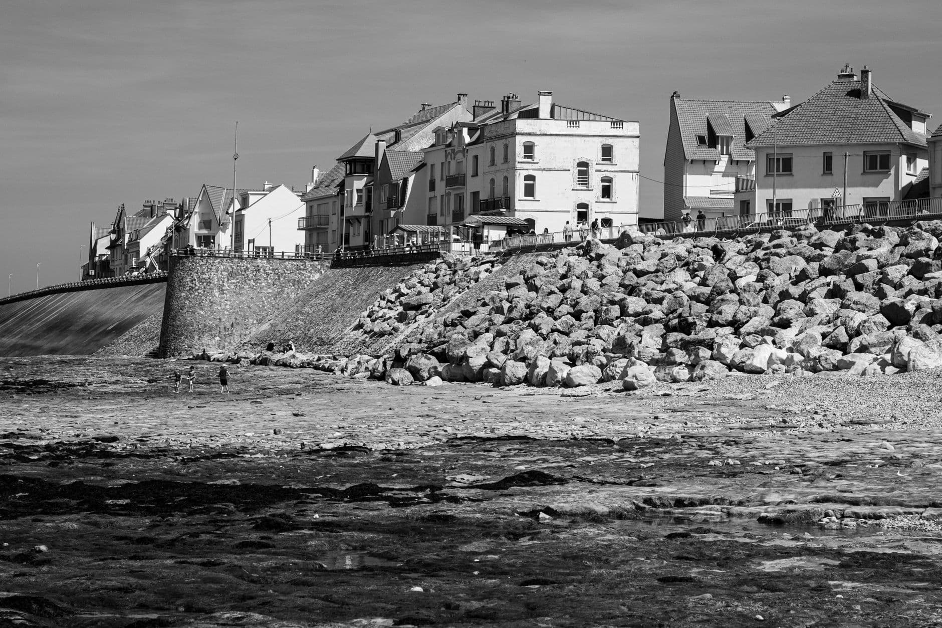 Scenic view of a coastal town with rocky shoreline in black and white.