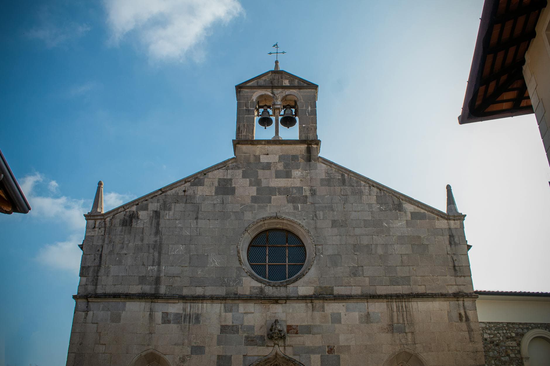 The facade of a historic church in San Daniele del Friuli, Italy, under a bright blue sky.