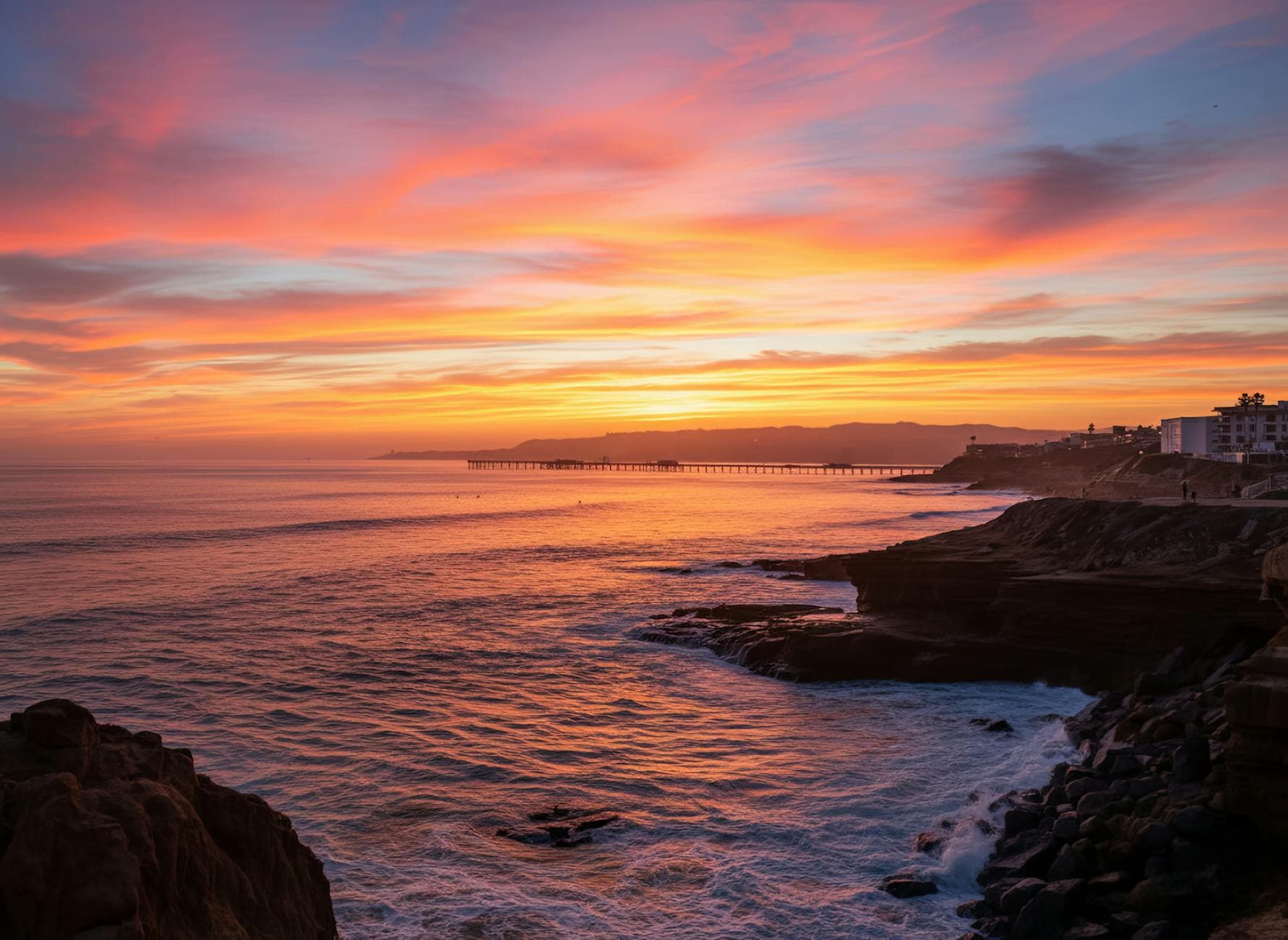 Dramatic sunset view of San Diego coastline with cliffs and pier, perfect for coastal wall art.
