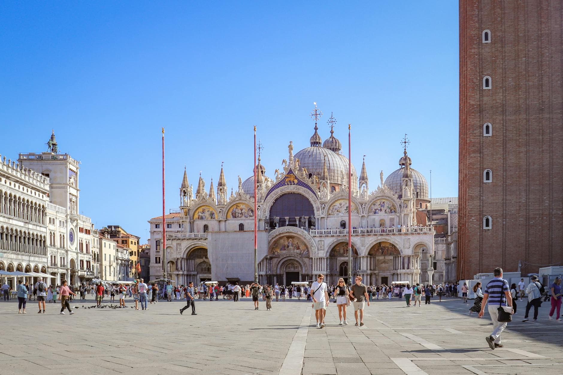 A vibrant scene of Saint Mark's Basilica in Venice, Italy, with people walking in the lively square.