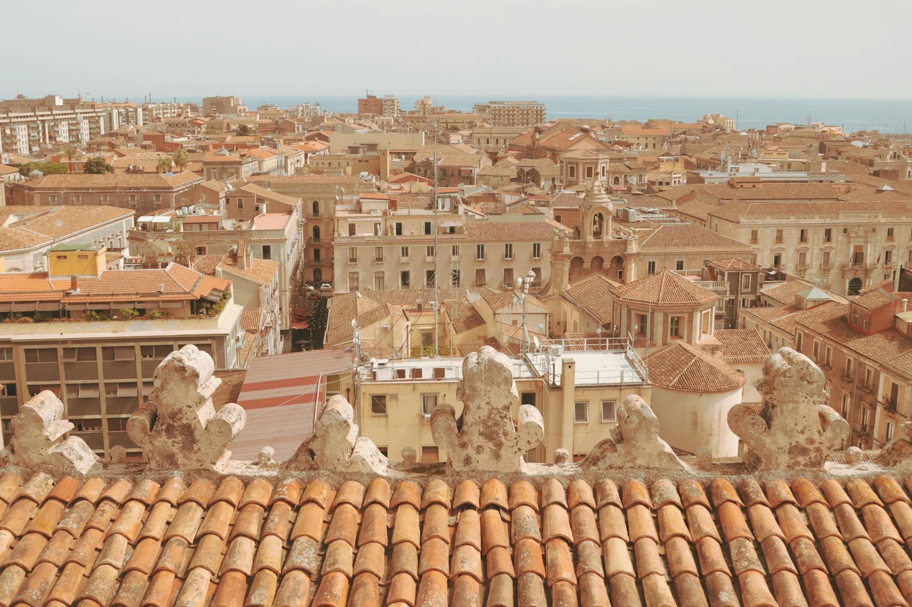 Aerial view of Catania cityscape with sea in the background, showcasing the historic architecture.