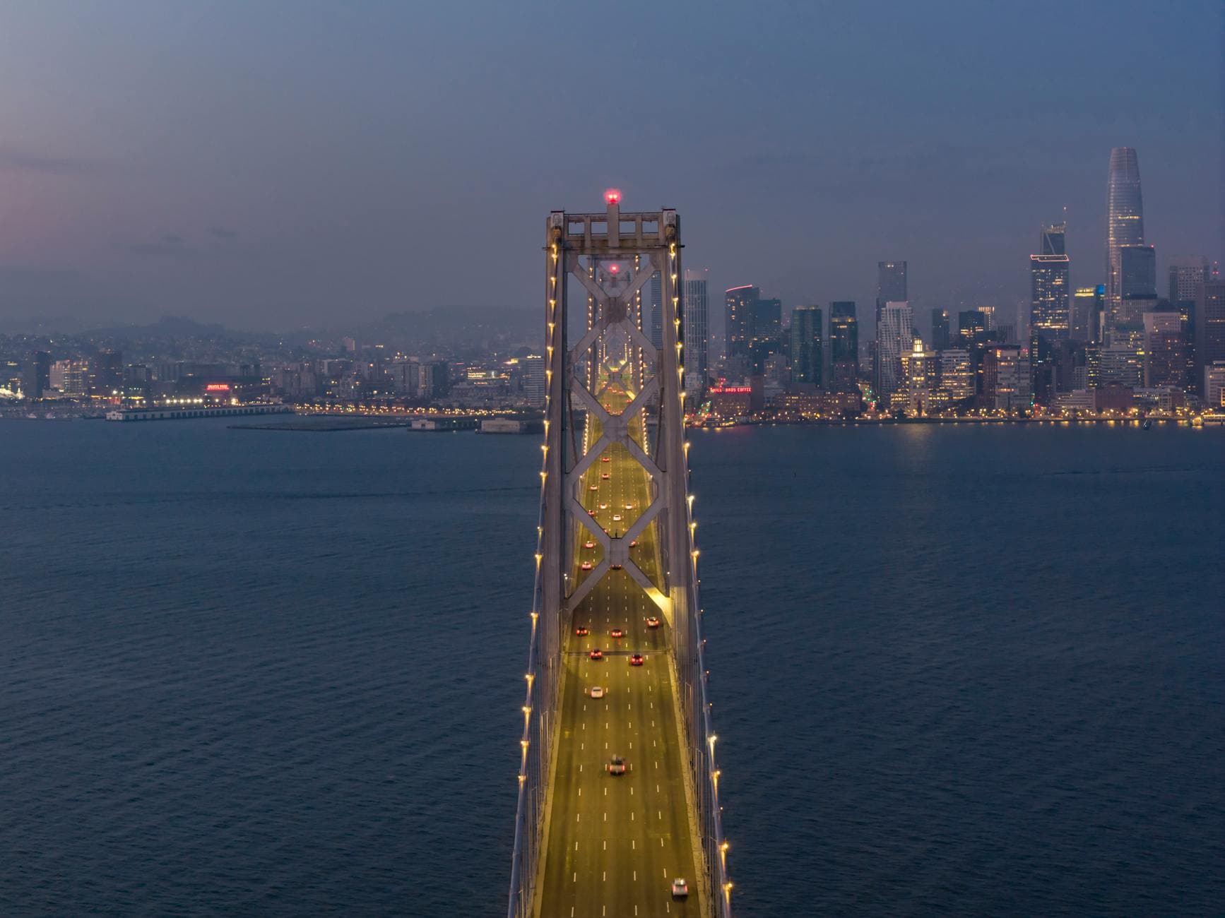 Stunning aerial view of the illuminated Bay Bridge and San Francisco skyline at twilight.