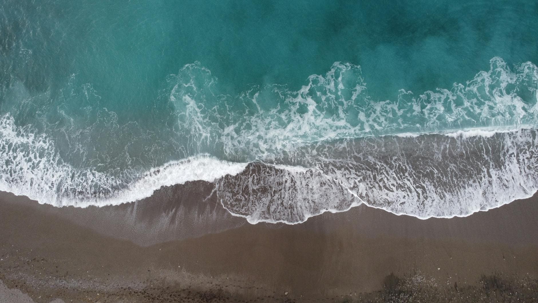 Aerial drone view of waves crashing on the sandy beach in Sorrento, Italy.