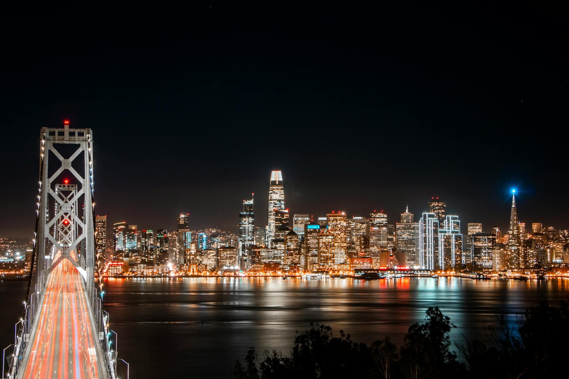 Stunning view of San Francisco skyline and Bay Bridge illuminated at night.