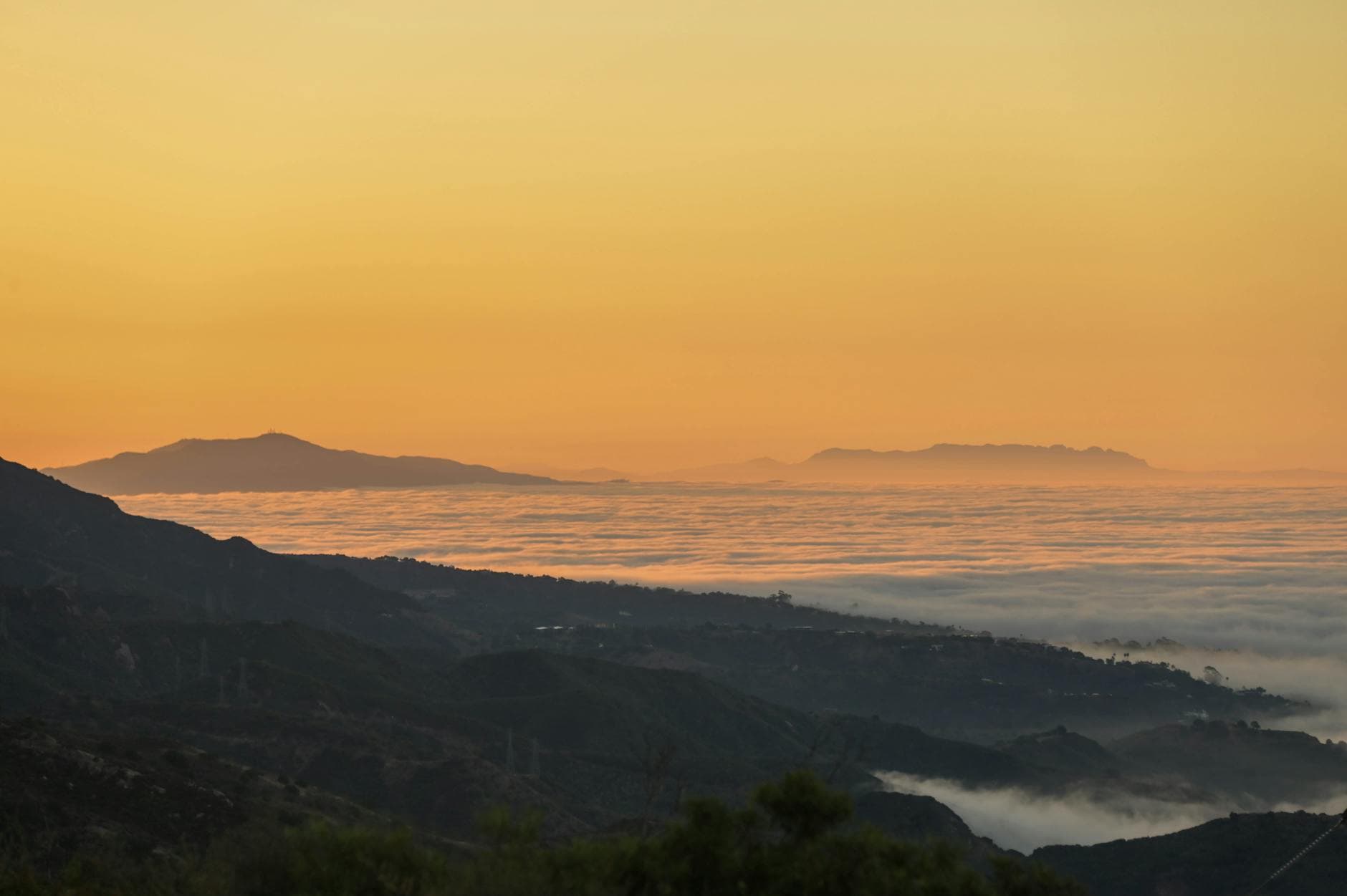 A breathtaking view of Santa Barbara's landscape during a serene sunrise, with misty clouds and mountain silhouettes.