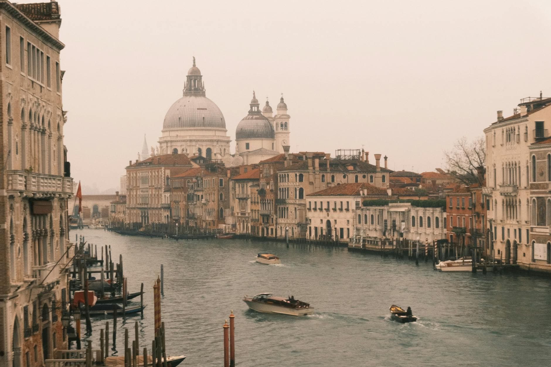 Beautiful view of Venice's Grand Canal with historic architecture and boats on a misty day.