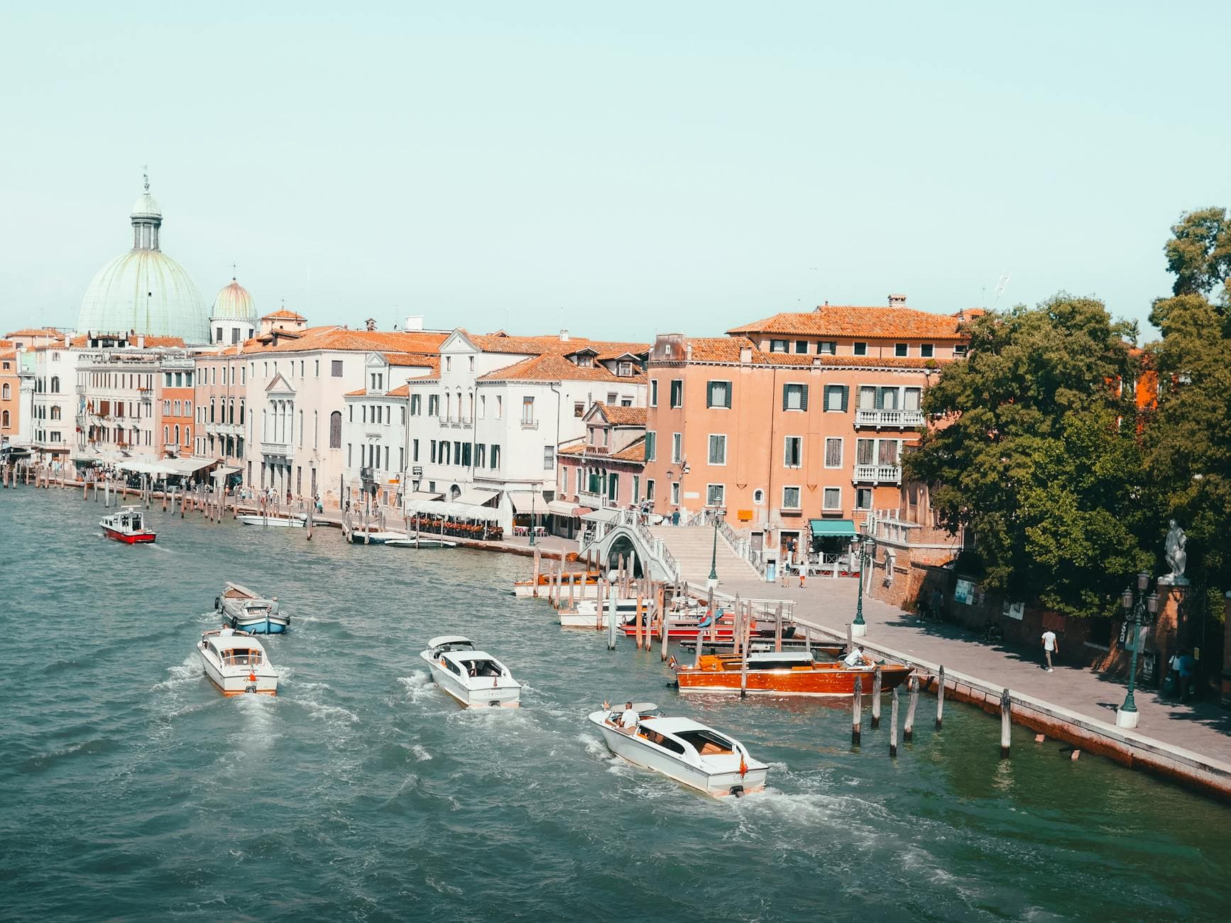A vibrant view of Venice's Grand Canal with boats and historic buildings, showcasing the city's unique charm.