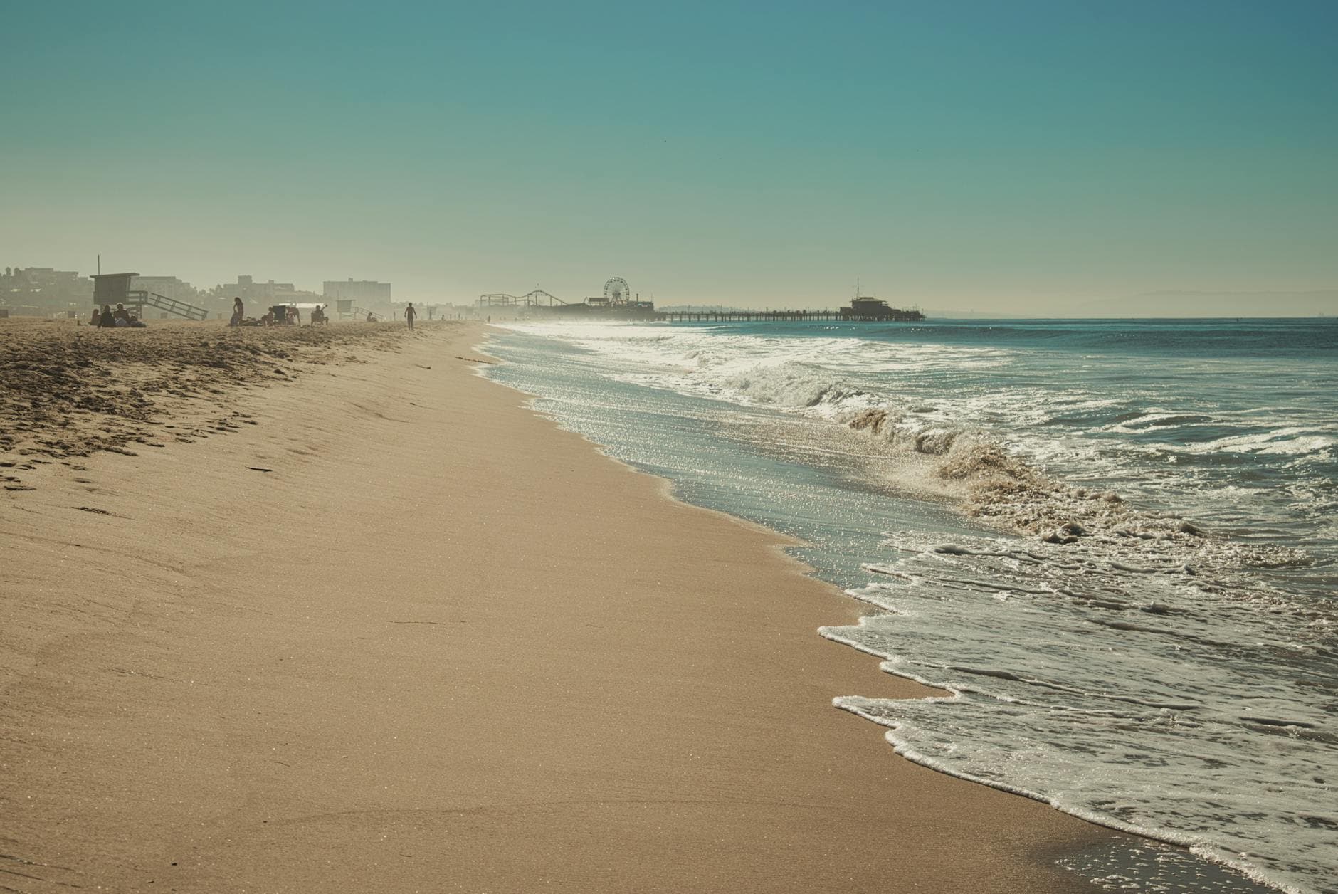 A serene view of Santa Monica Beach showcasing the iconic pier under a clear sky.