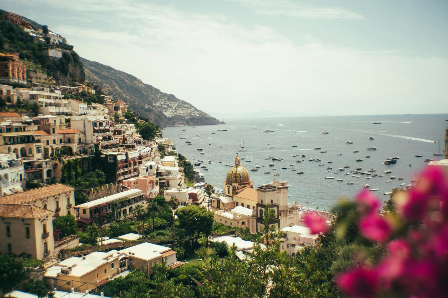 Scenic view of Positano's iconic cliffside and azure Mediterranean Sea with vibrant flowers.