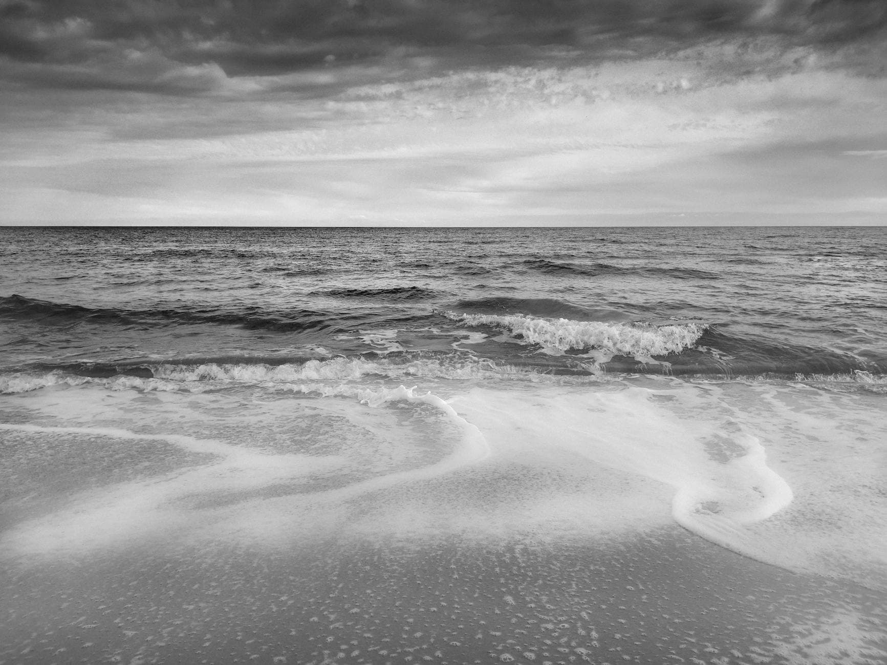 Peaceful black and white view of waves on a beach in Santa Margherita di Pula, Sardinia.