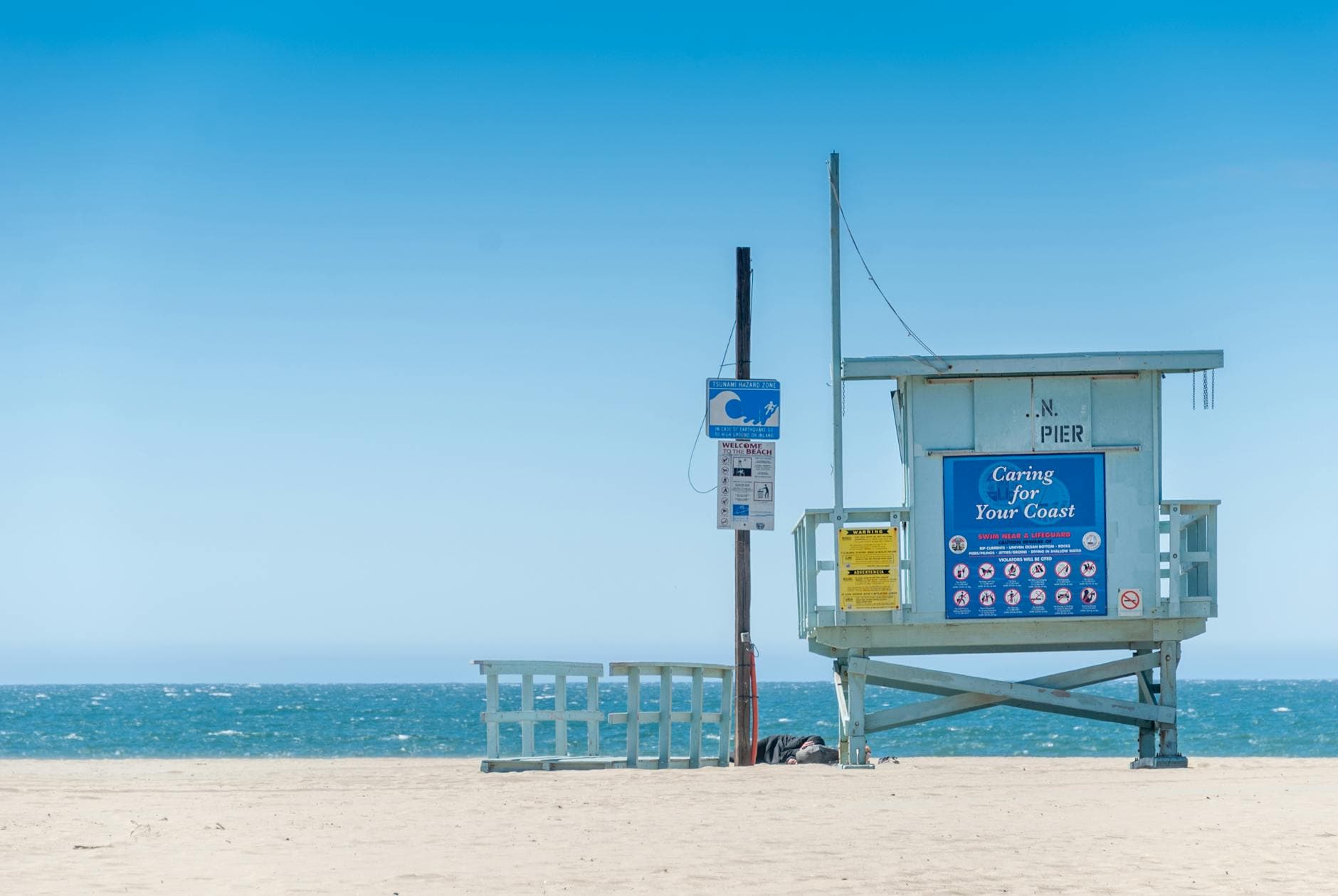 A lifeguard tower at Santa Monica Beach with clear blue skies and ocean view, perfect for coastal safety and leisure vibes.