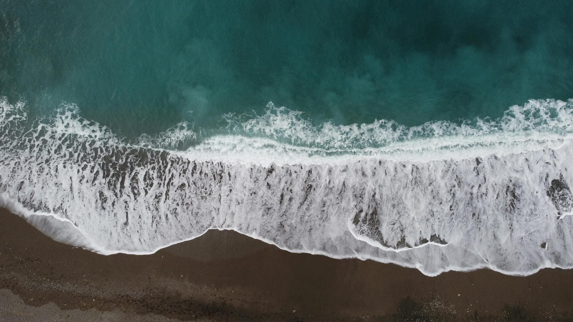 A serene aerial view of waves crashing onto the shore of Sorrento, Italy.