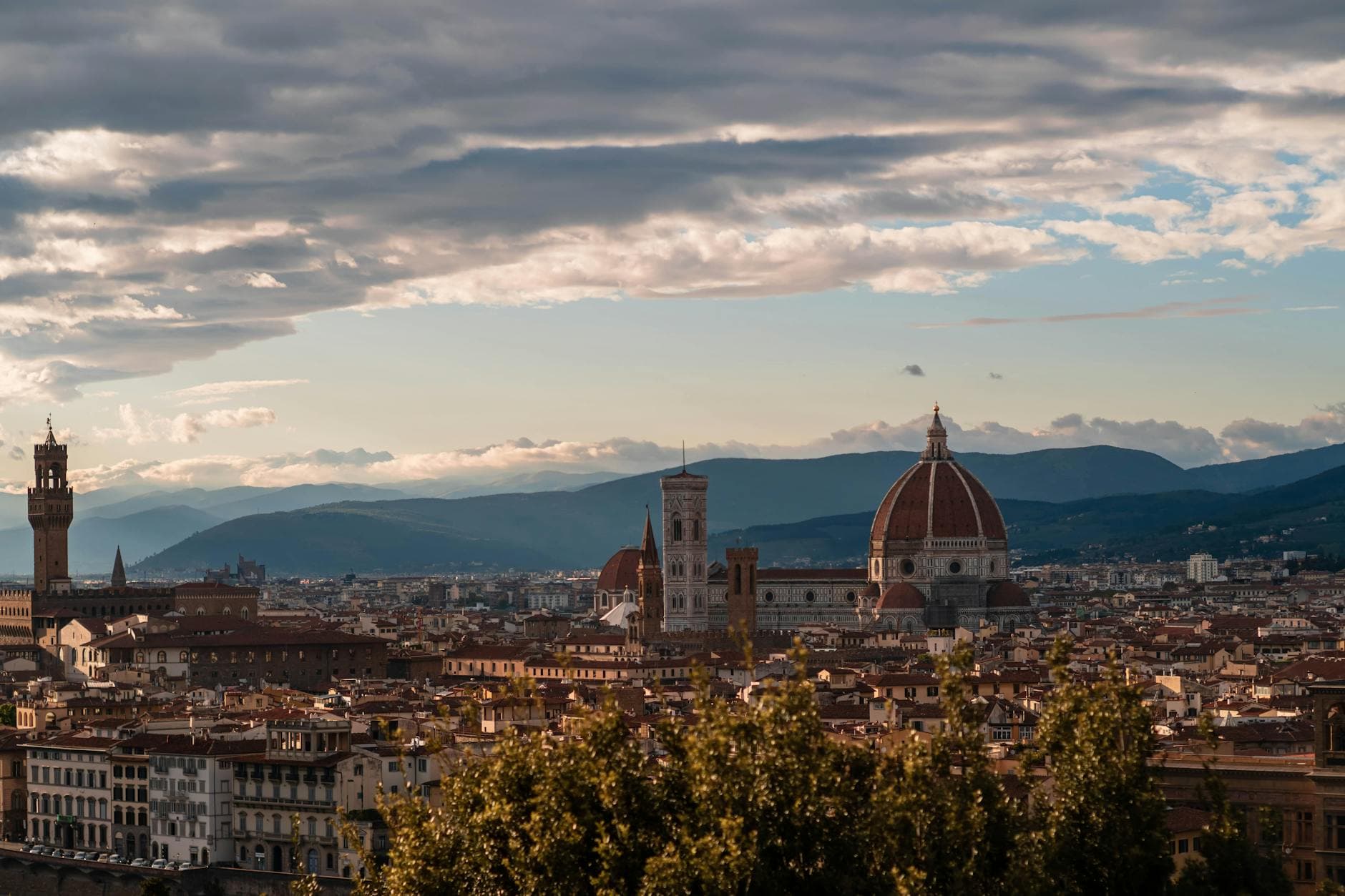Stunning Florence cityscape featuring the iconic Florence Cathedral and Palazzo Vecchio against a mountainous backdrop.