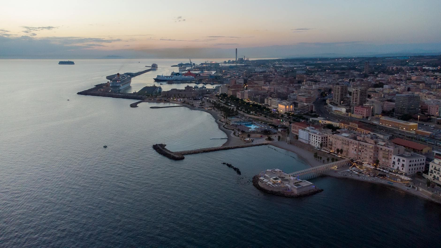 Stunning aerial view of Civitavecchia, Italy's coastline captured at dusk, showcasing the city's vibrant urban and coastal landscape.