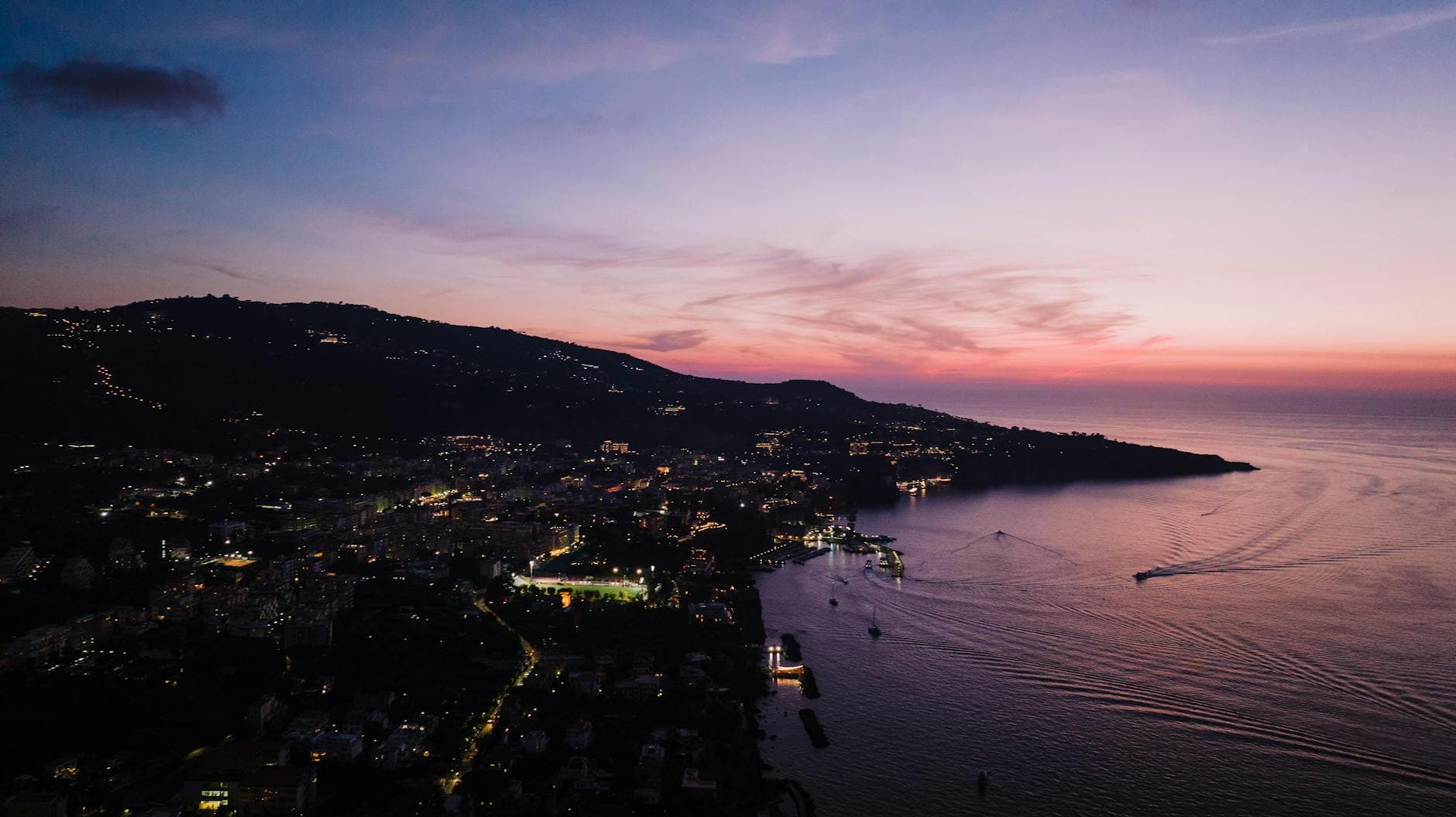 A breathtaking twilight view of Sant'Agnello, Italy, showcasing the serene seascape and vibrant town lights.