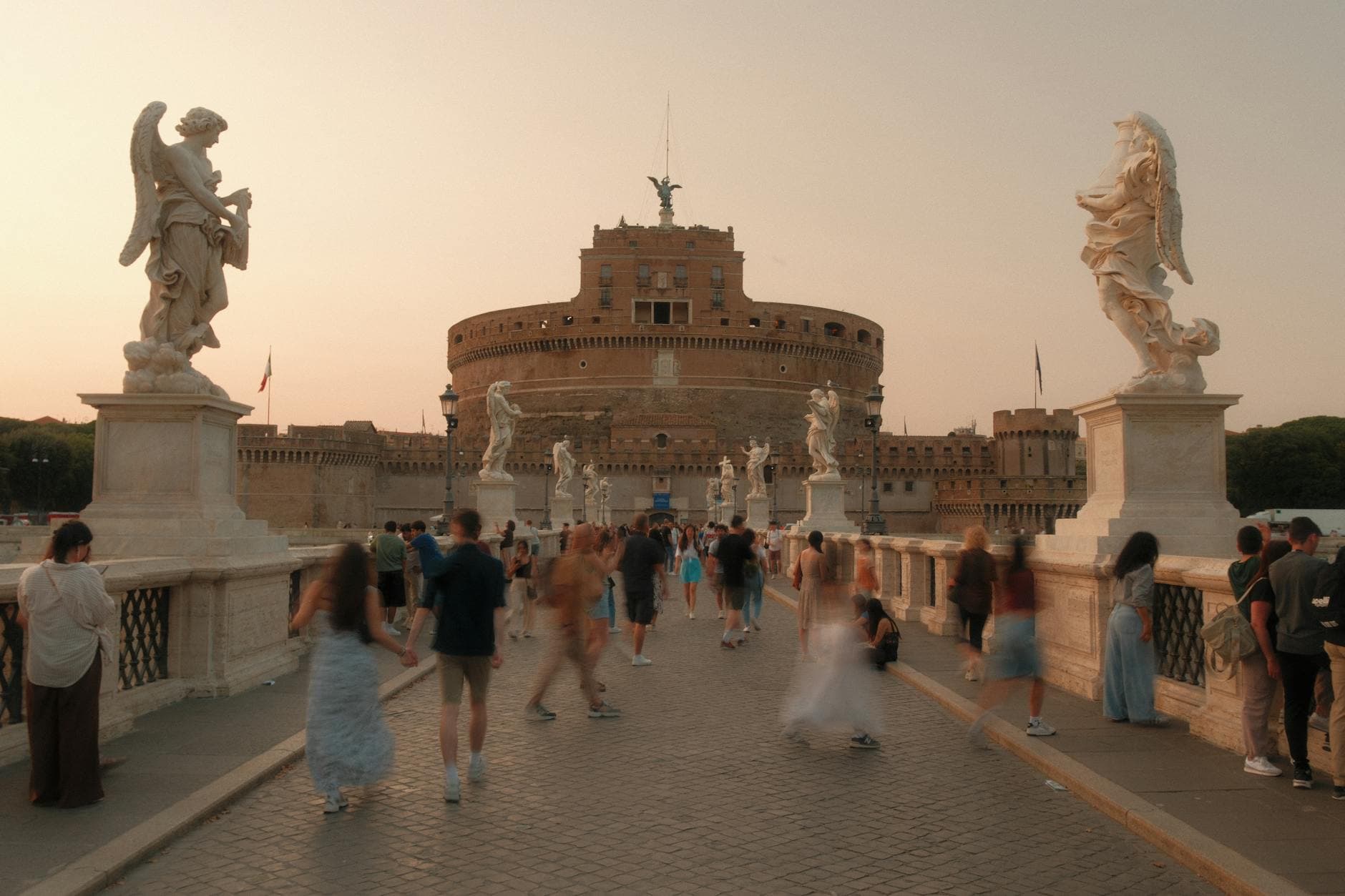 Pedestrians on Sant'Angelo Bridge at sunset, Castel Sant'Angelo in Rome.