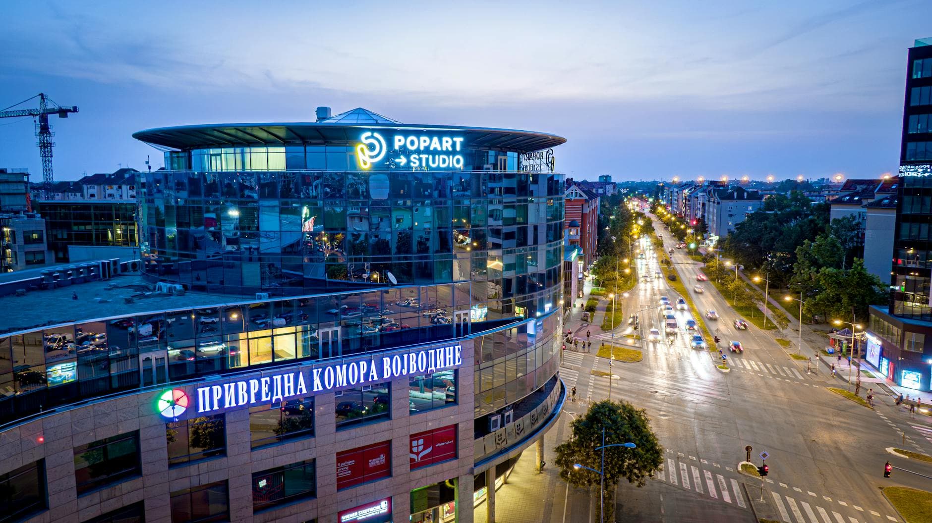 A stunning view of an urban street in Novi Sad, Serbia at dusk, featuring modern architecture.