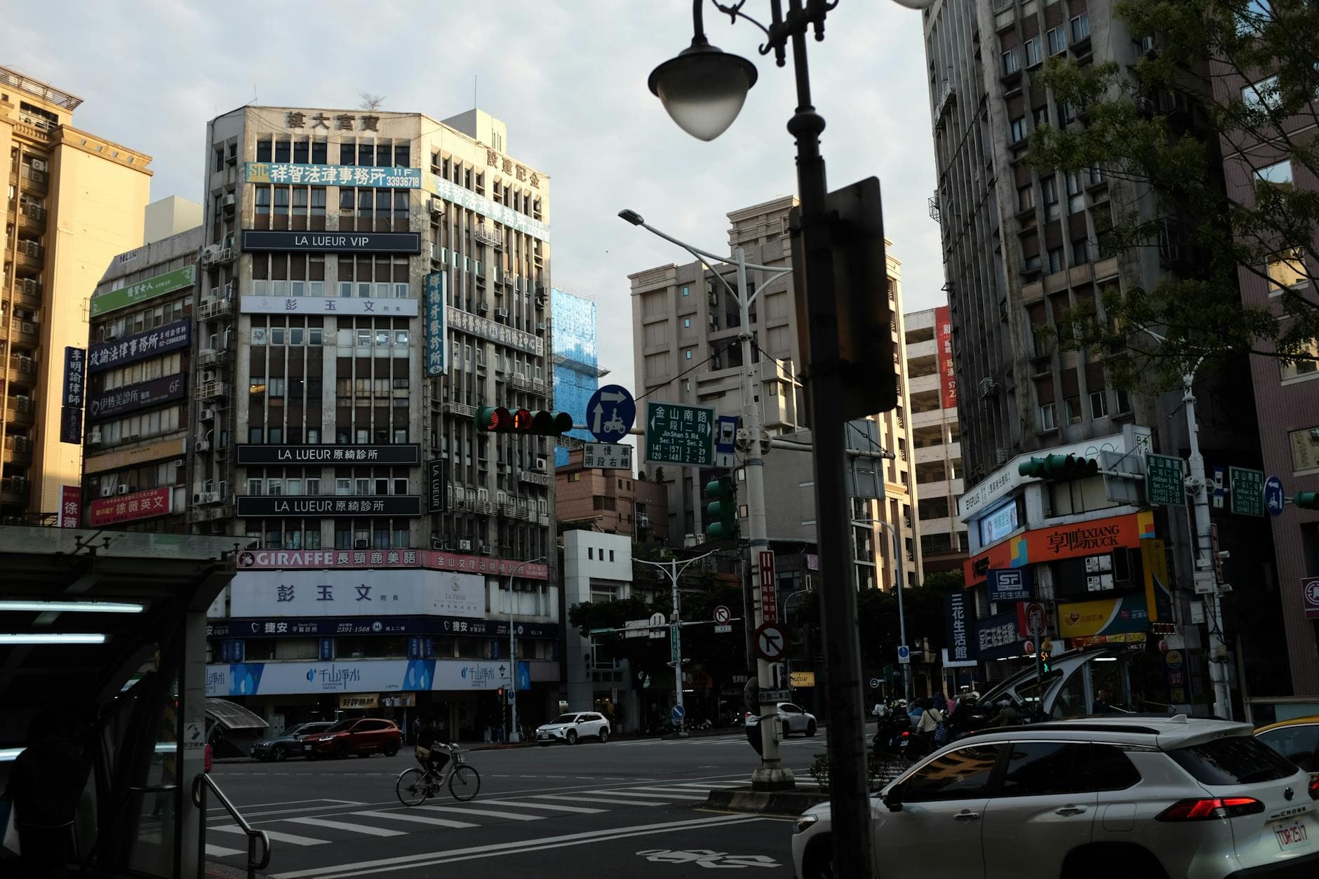 A busy urban intersection with high-rise buildings and traffic in an Asian city.