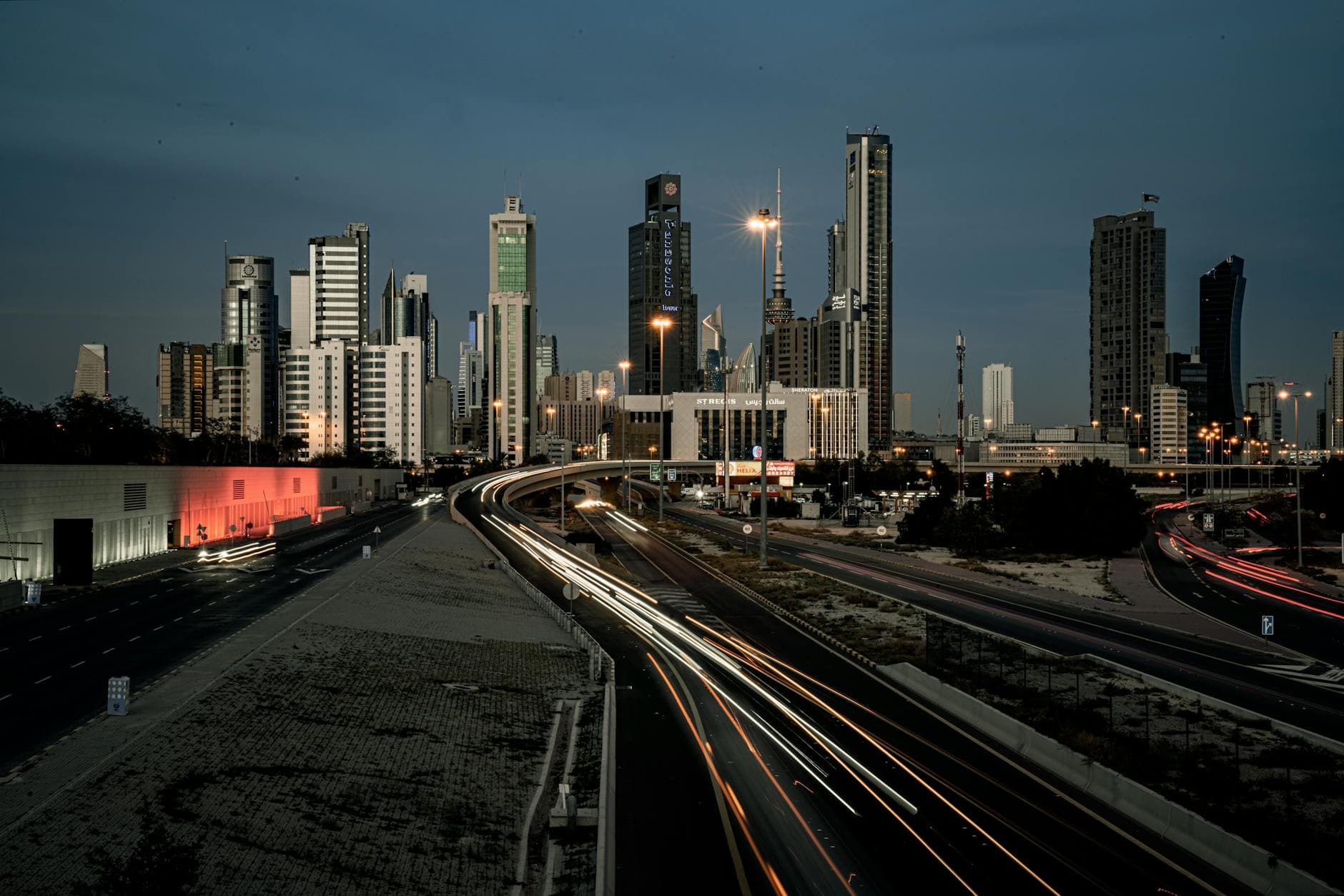 Twilight view of Kuwait City's modern skyline and streets with light trails.