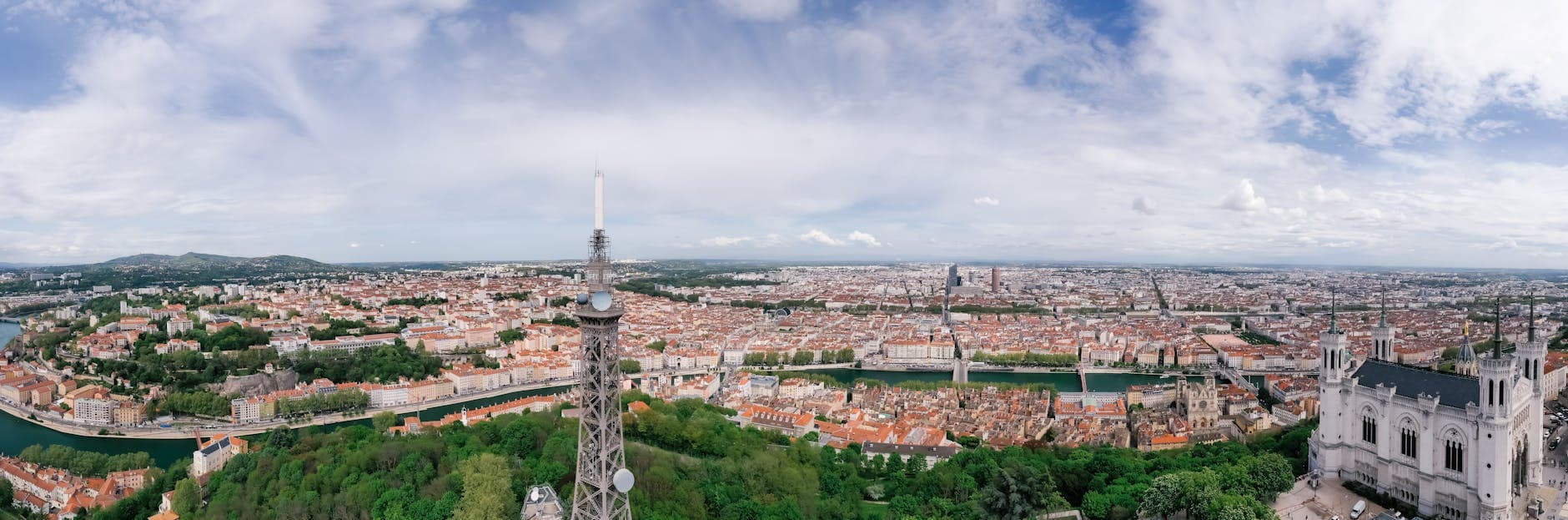 A panoramic aerial view showcasing Lyon's cityscape with lush greenery and historical landmarks.