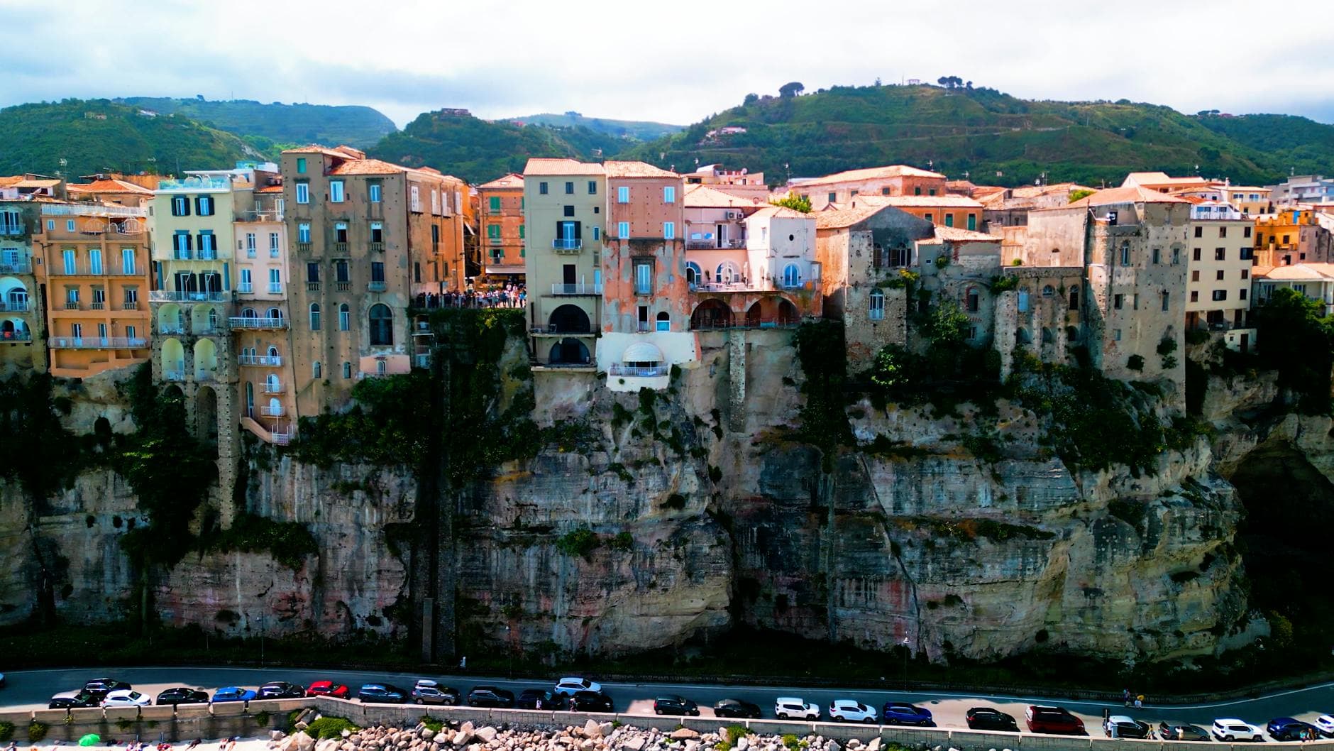 A breathtaking view of Tropea, Italy, with historic buildings perched on majestic cliffs under a vibrant sky.