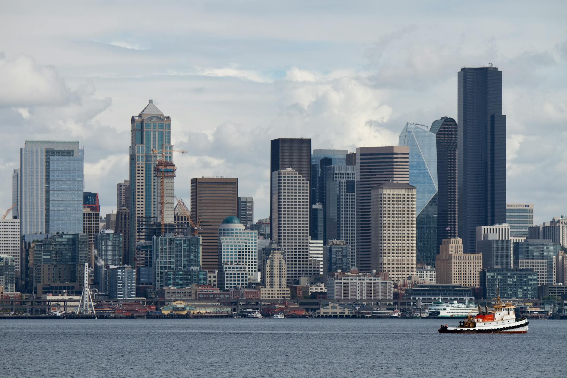 Beautiful view of Seattle's downtown skyline with a boat on the waterfront during the day.