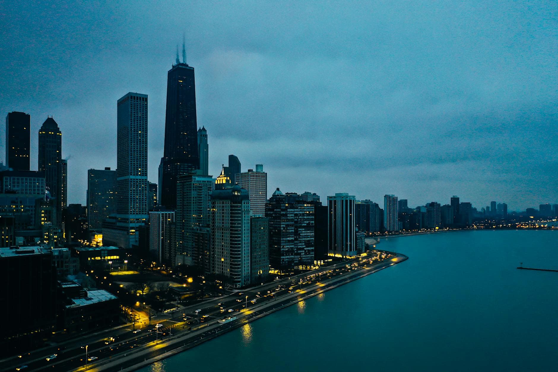 Stunning aerial view of downtown Chicago skyline at twilight, showcasing illuminated skyscrapers along the waterfront.