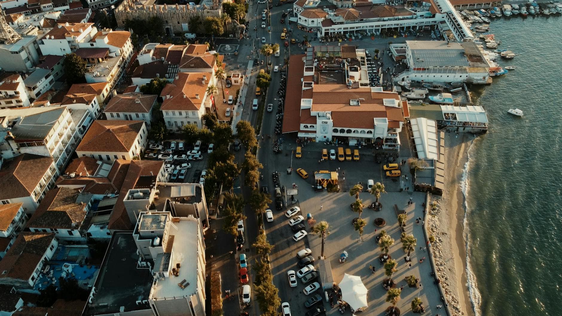 Aerial view of Kuşadası, a vibrant coastal city in Türkiye, during golden hour with waterfront and urban architecture.