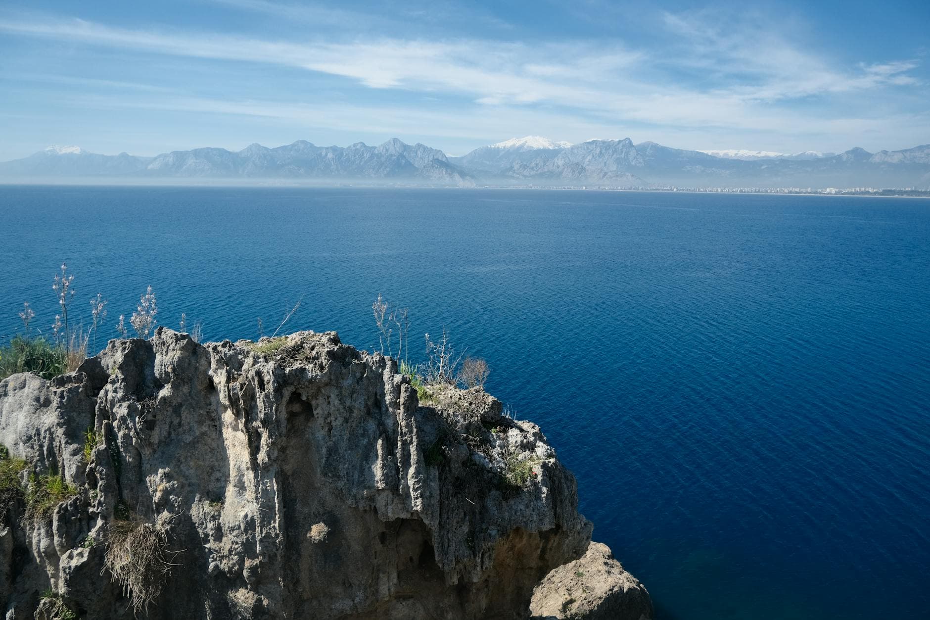 Scenic view of Antalya's coastline with cliffs and mountains under a clear blue sky.