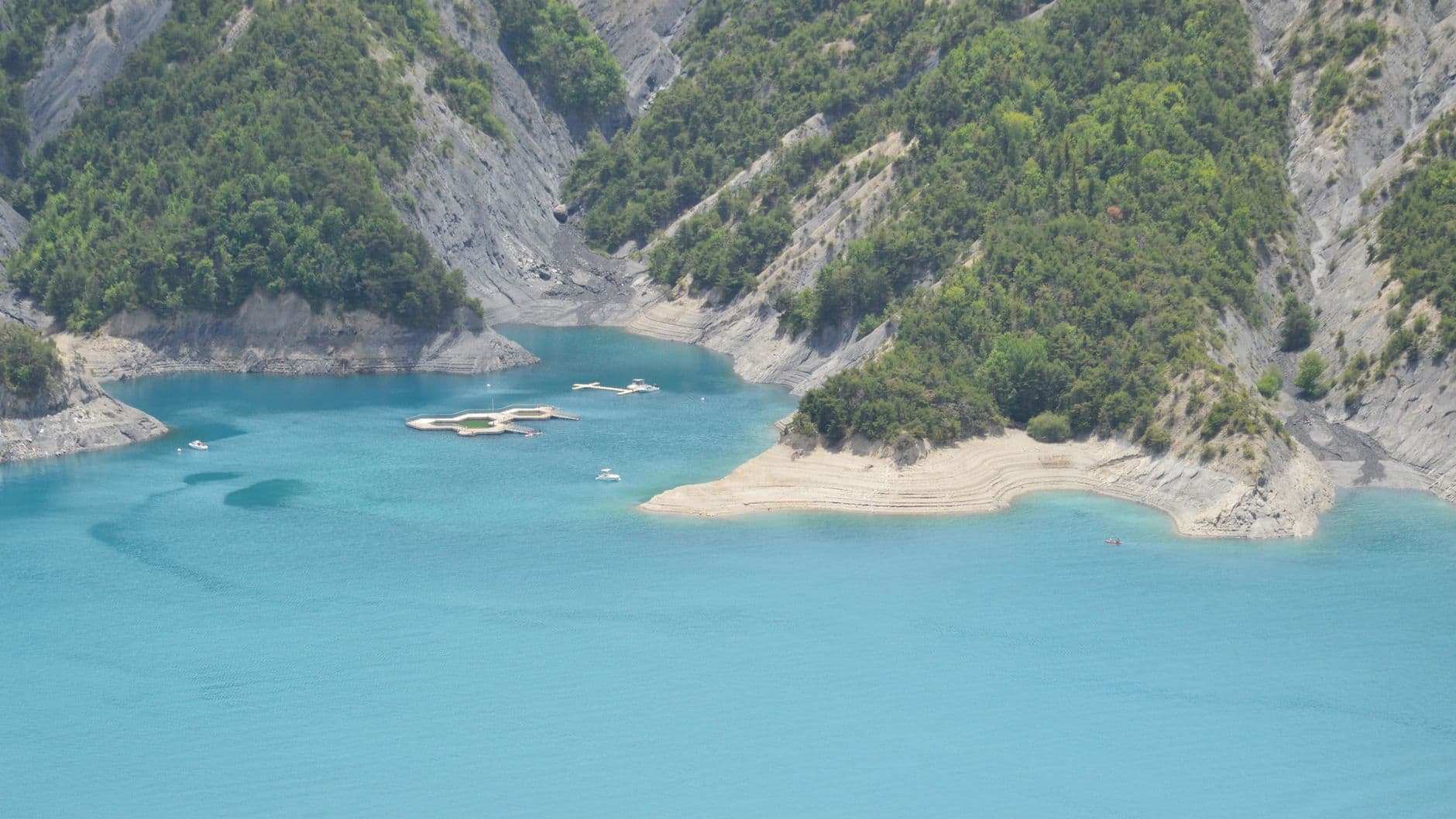 A breathtaking aerial view of Ubaye-Serre-Ponçon lake with turquoise waters and lush mountains.