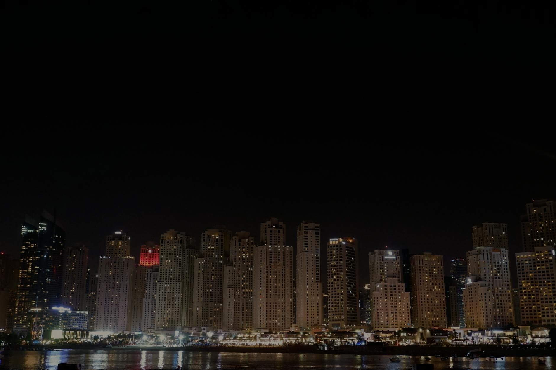A stunning view of Dubai Marina's skyline reflecting on the waterfront under a night sky.