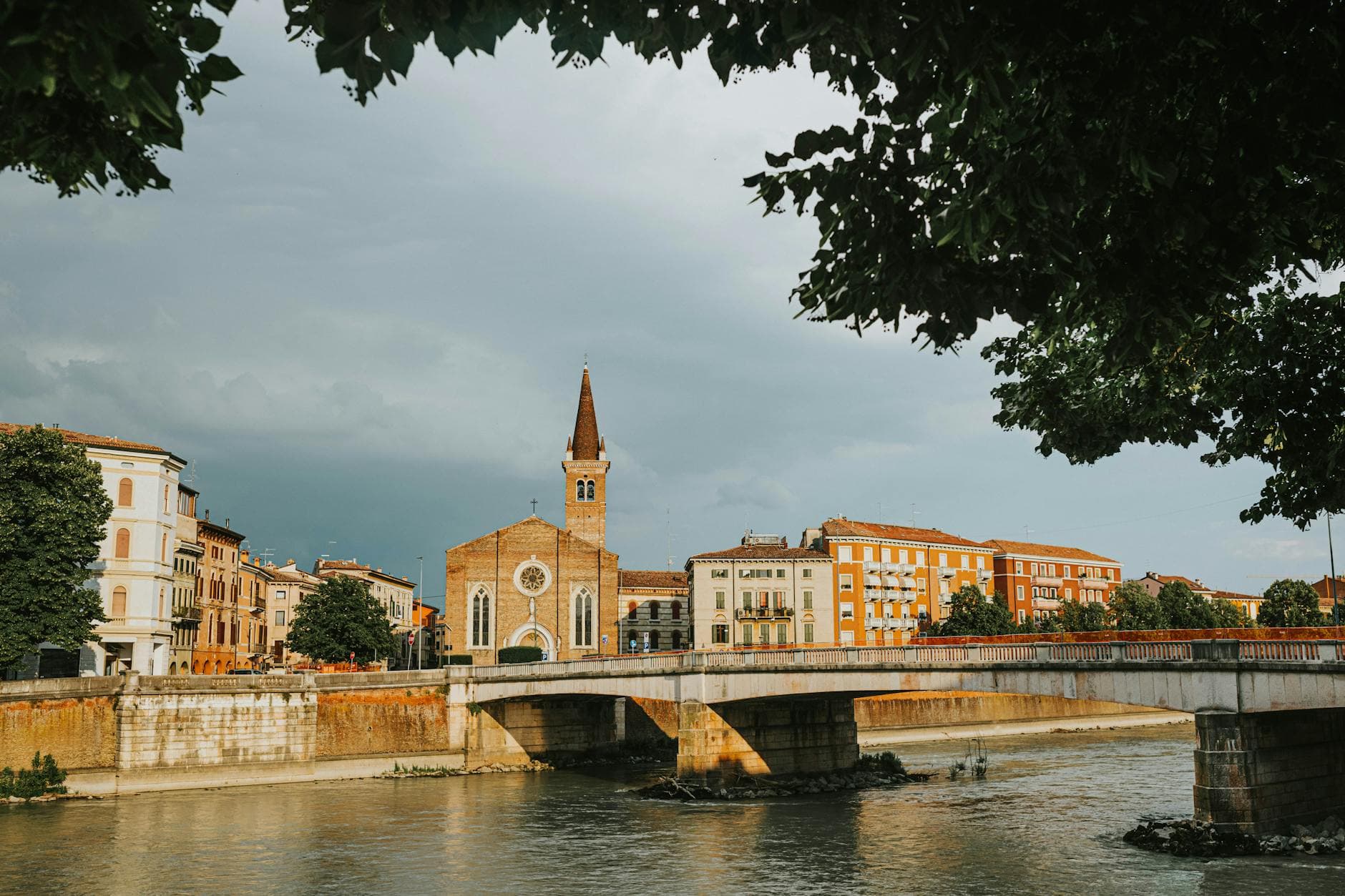 Beautiful view of a historic bridge over the river in Verona, Italy, under a cloudy sky.