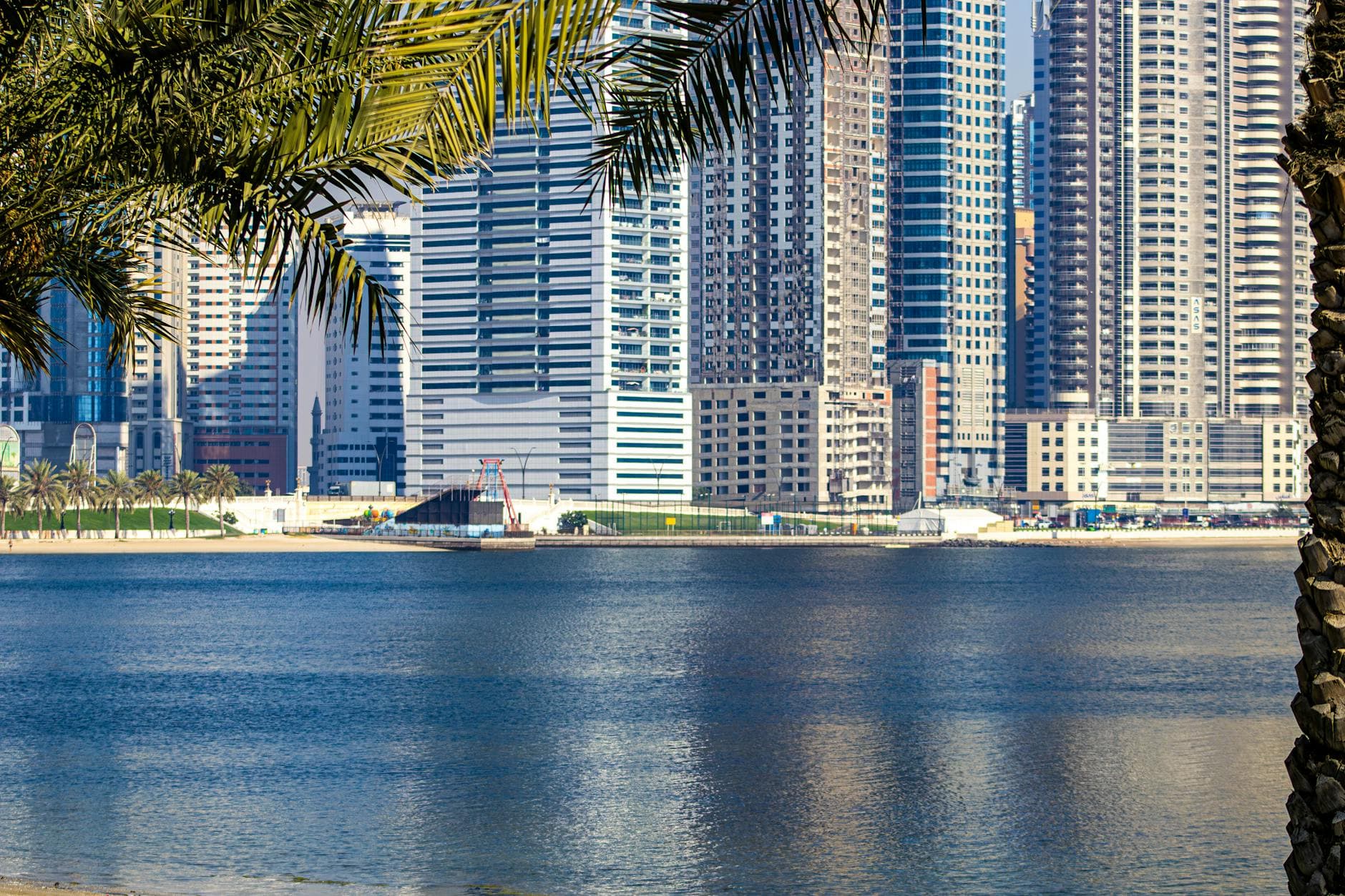 Modern skyscrapers reflecting on the waterfront in Sharjah, UAE.