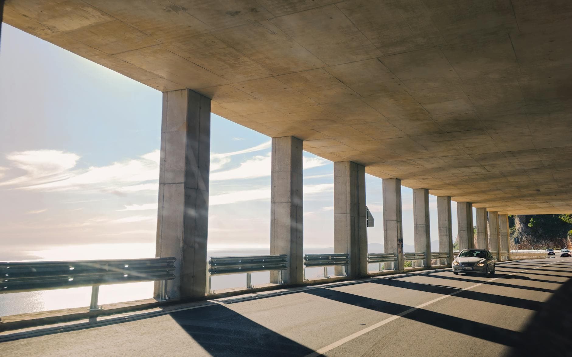 Car driving through a concrete tunnel with ocean views in Shëngjin, Albania.