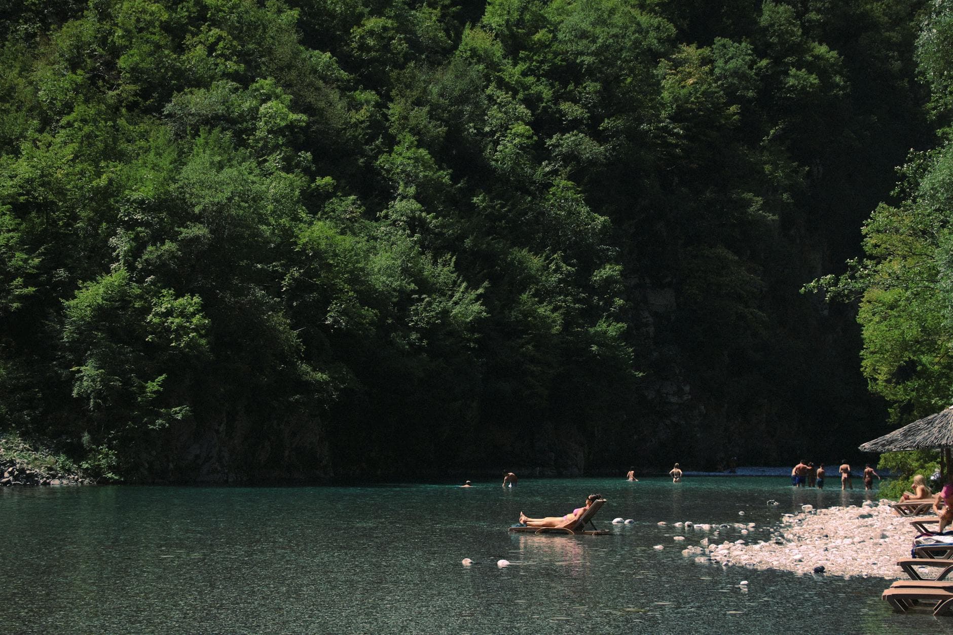 People enjoying a relaxing day at a scenic lakeside beach in Shkodër County, Albania.