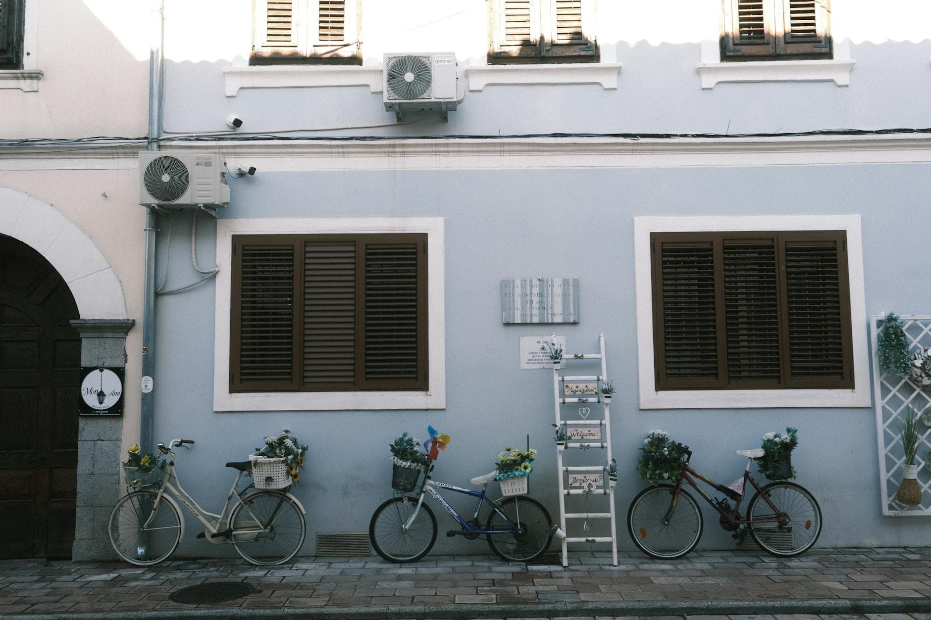 Charming street view with bicycles and flowers against a pastel wall in Shkodër, Albania.