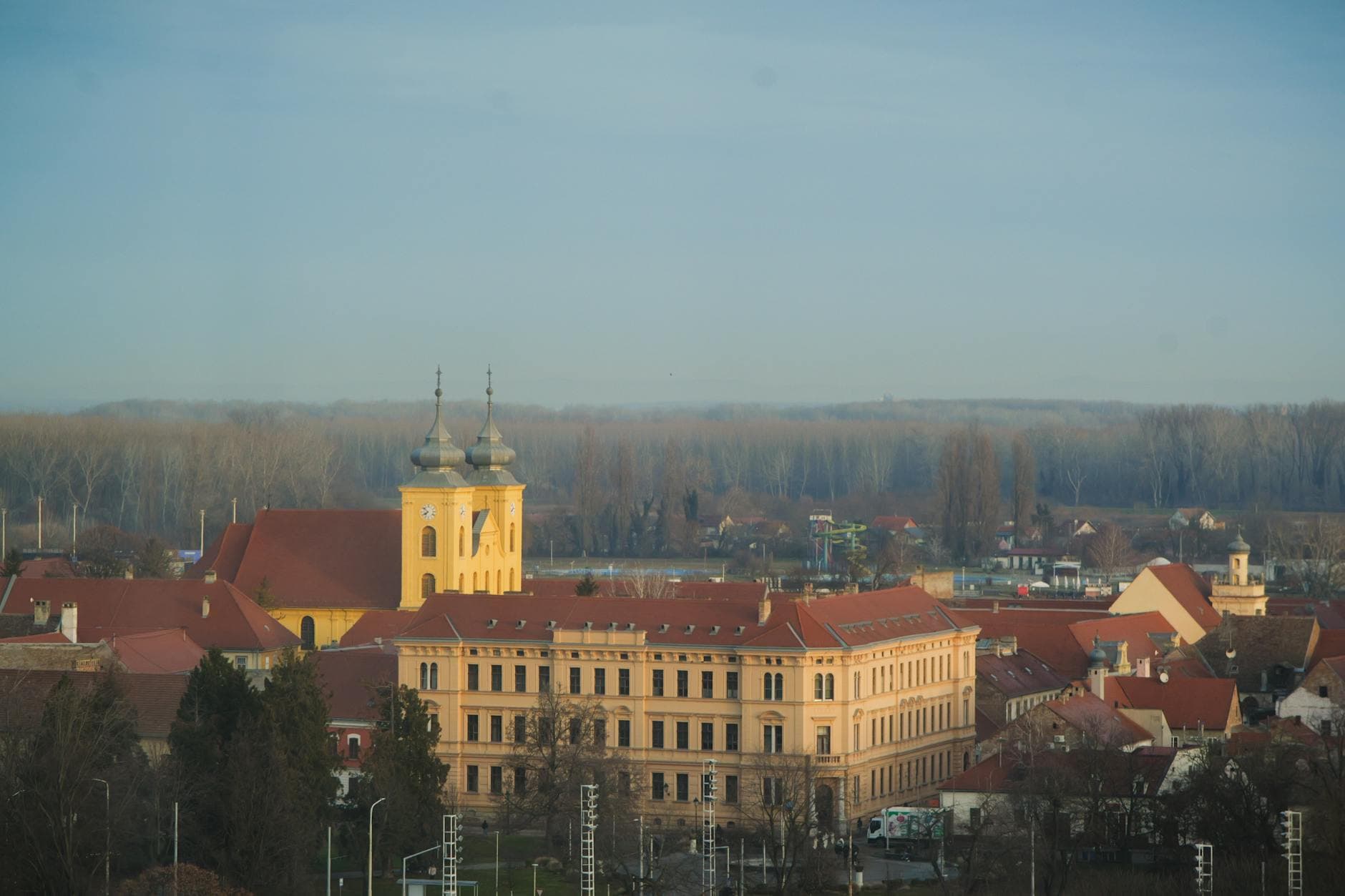 Aerial view of a historic European cityscape featuring a yellow church and surrounding buildings at day.
